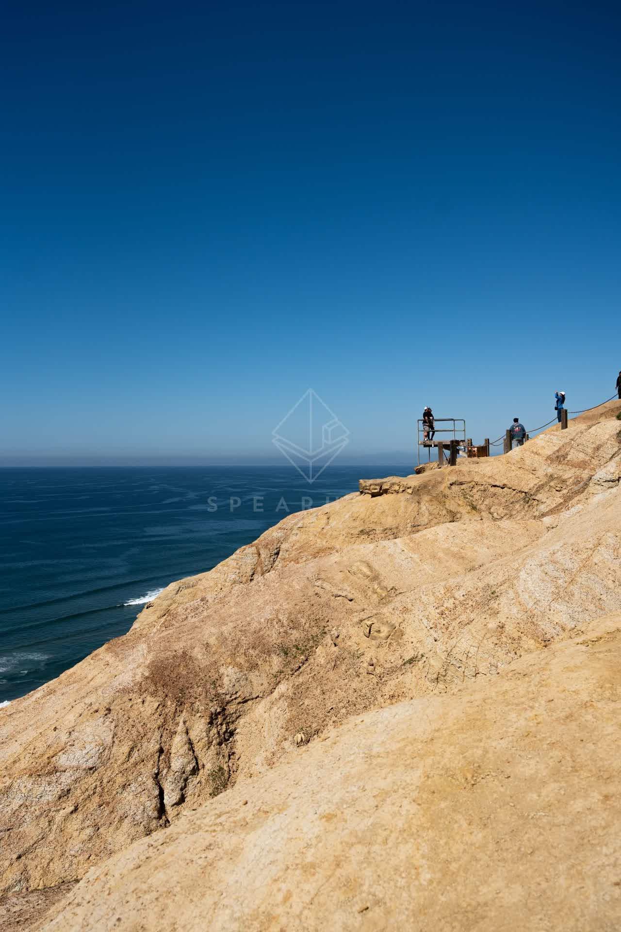 Elevated view of the cliffs, the ocean and open country at Torrey Pines, with people walking.