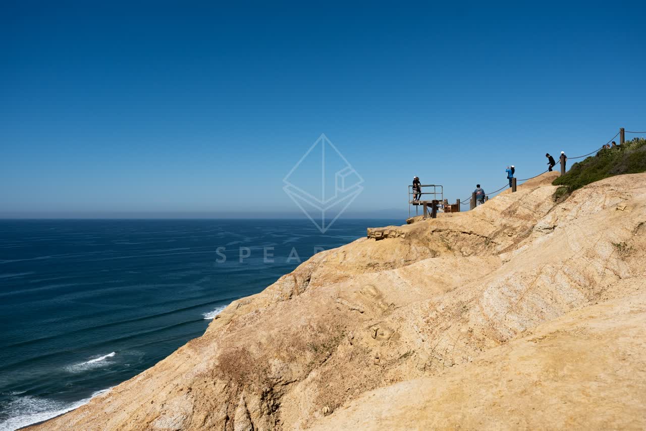 Elevated view of the cliffs, the ocean and open country at Torrey Pines, with people walking.
