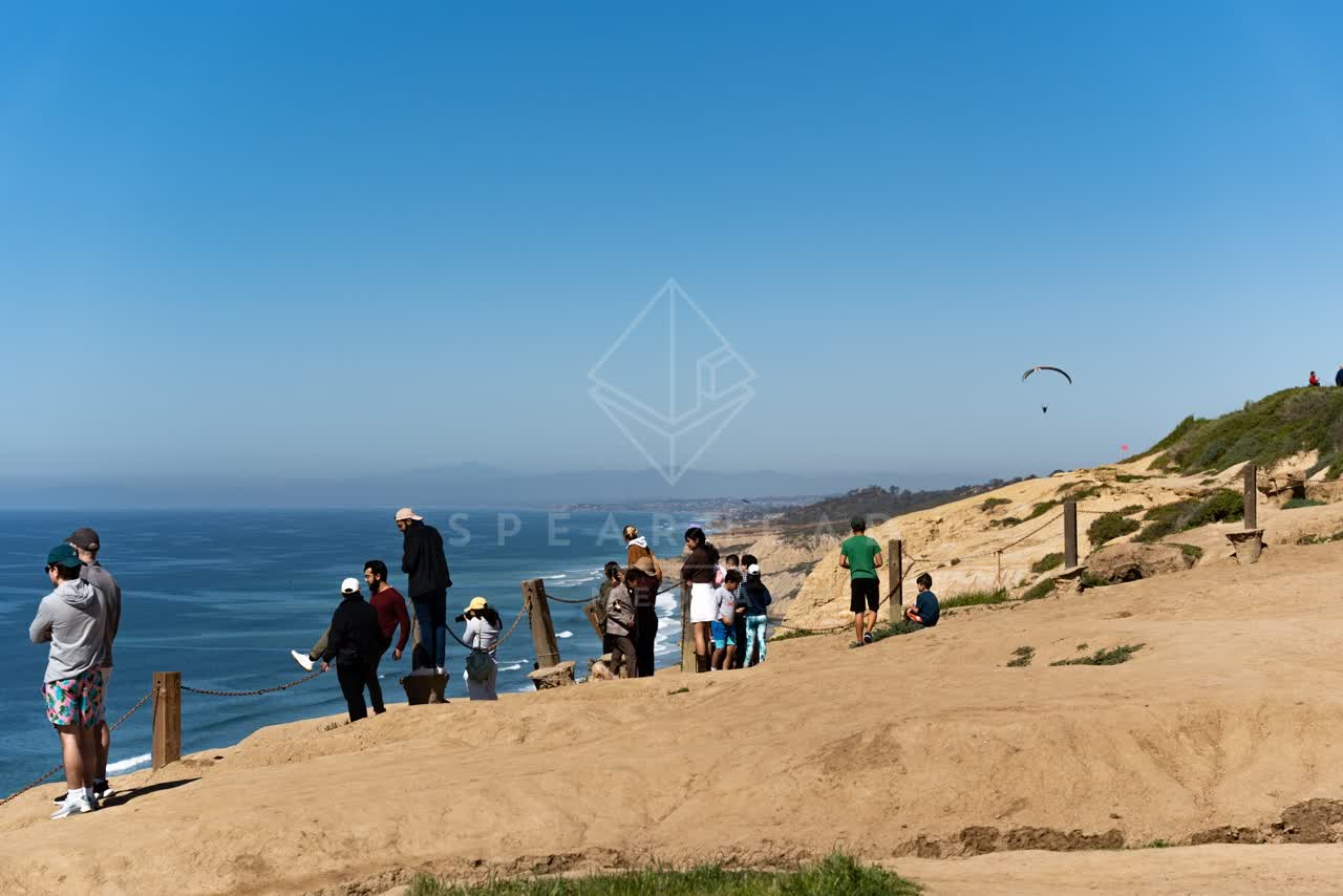 Elevated view of the cliffs, the ocean and open country at Torrey Pines, with a crowd gathered.