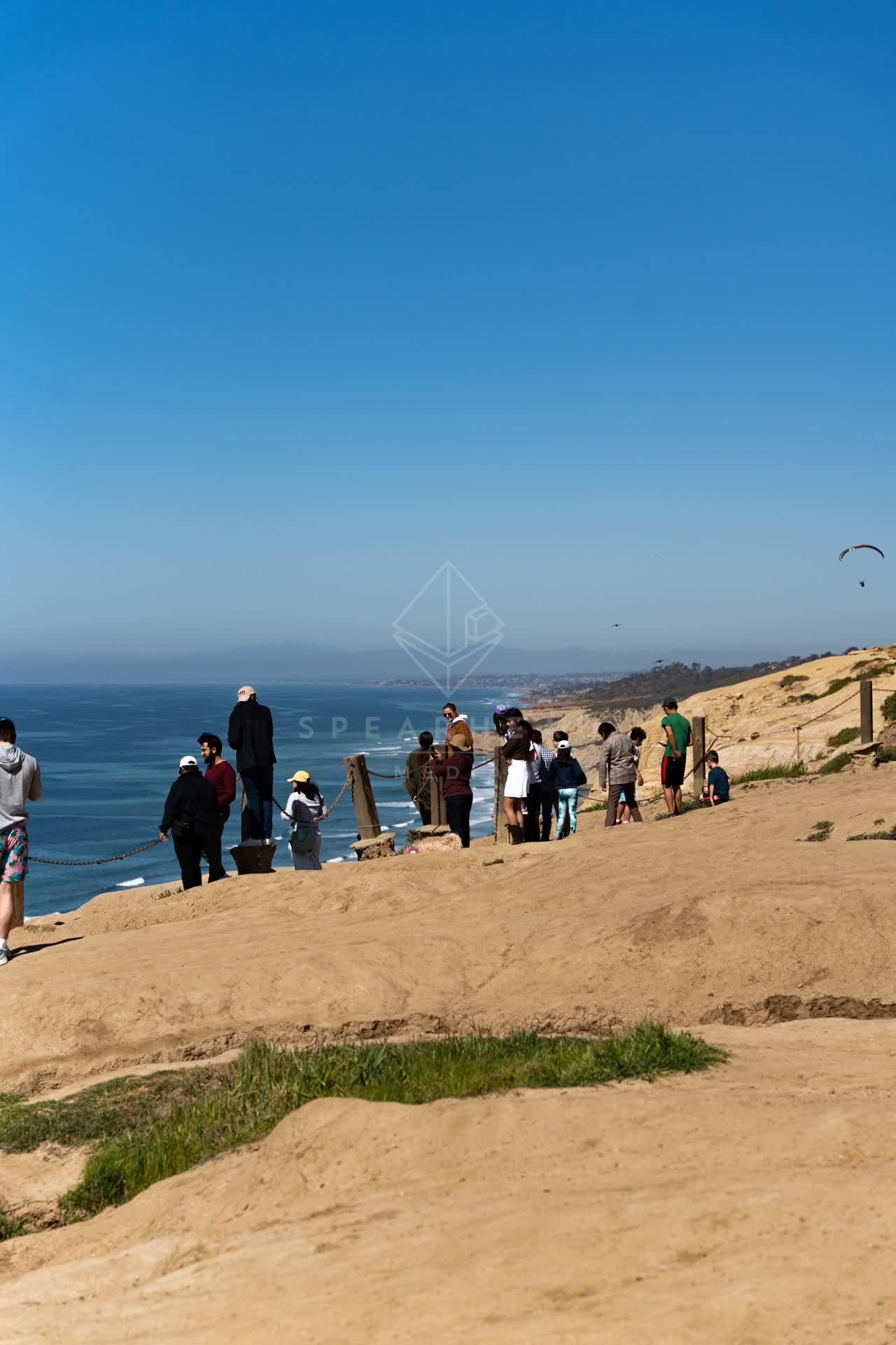 Elevated view of the cliffs, the ocean and open country at Torrey Pines, with people walking.