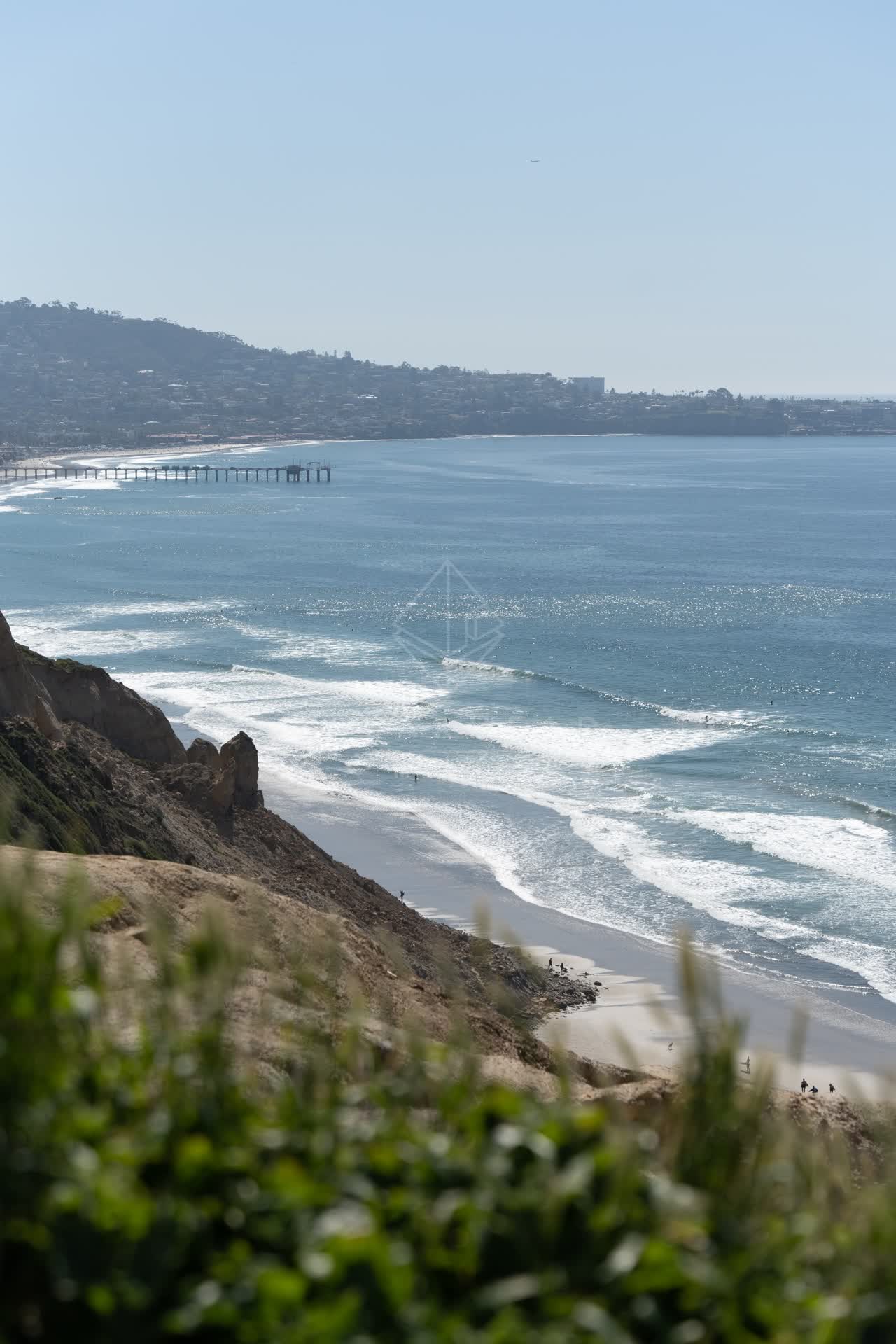 Elevated view of the cliffs, the pier and the ocean at Torrey Pines, with people walking.