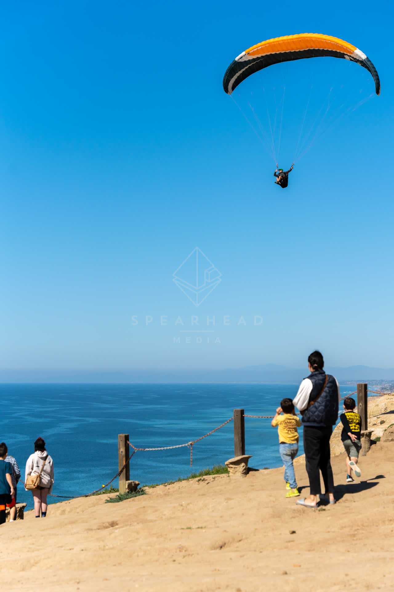 Elevated view of the cliffs, the ocean and open country at Torrey Pines, with a crowd gathered.