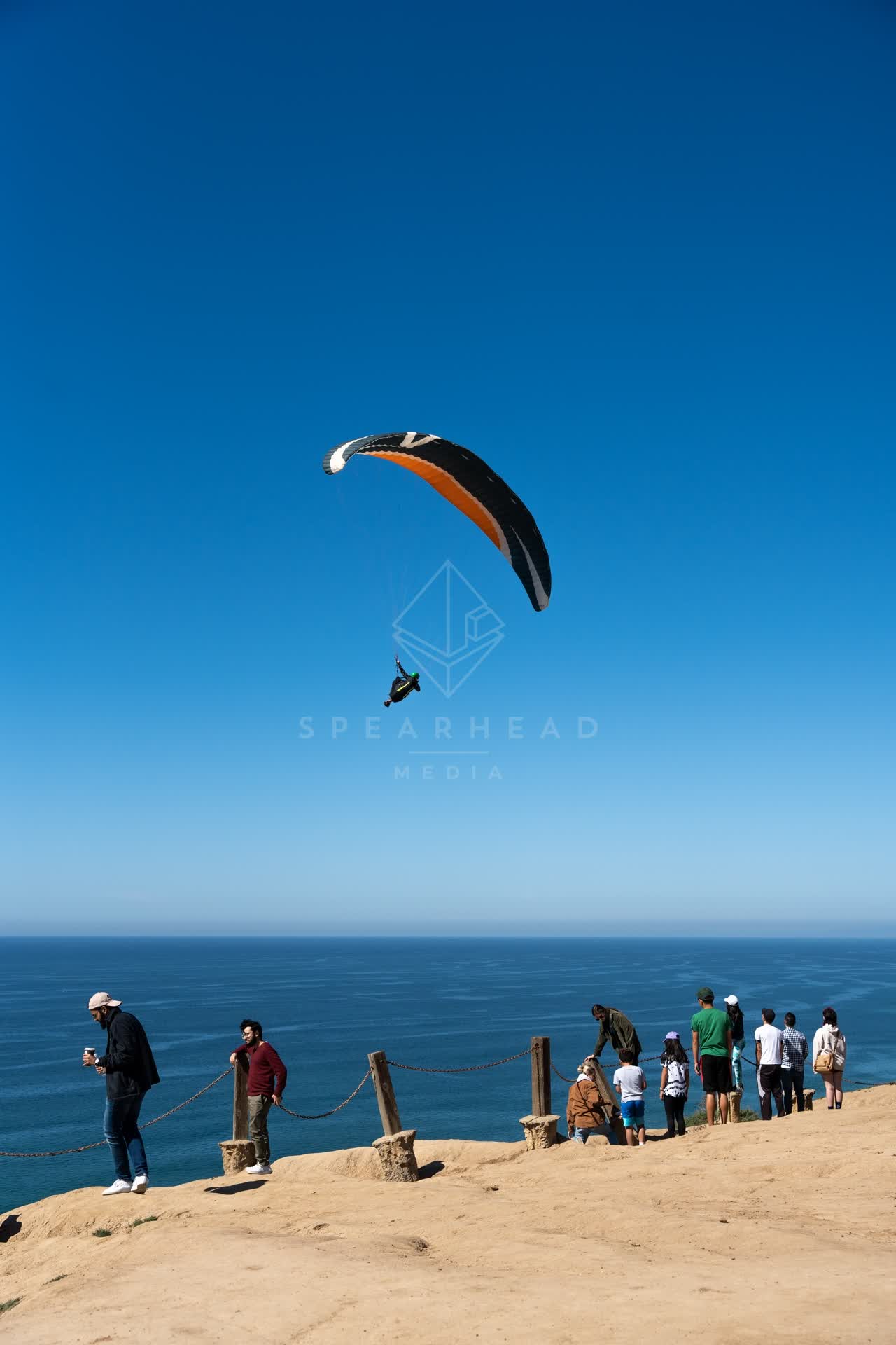 Elevated view of the cliffs, the ocean and open country at Torrey Pines, with a crowd gathered.