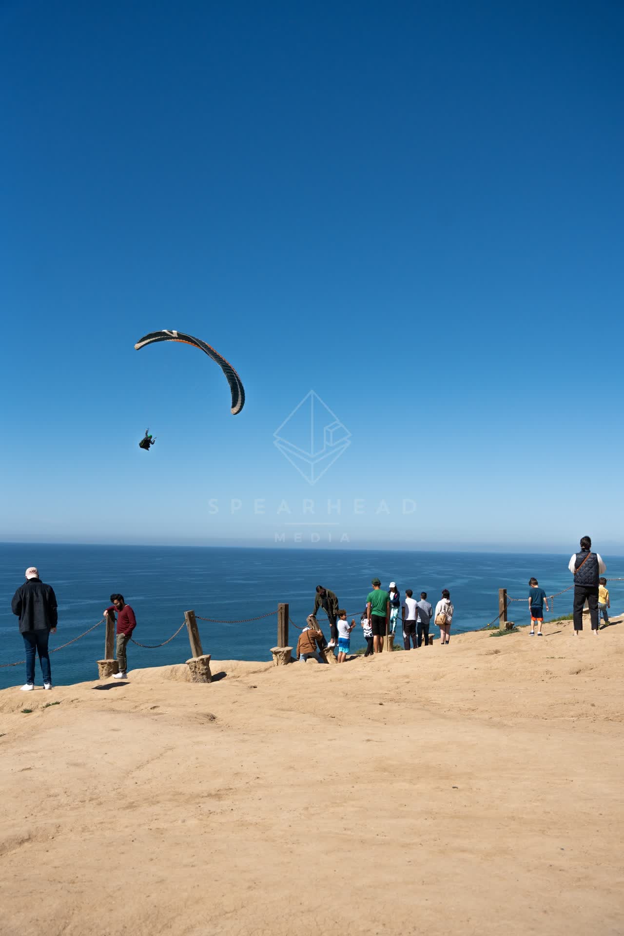 Elevated view of the cliffs, the ocean and open country at Torrey Pines, with a crowd gathered.