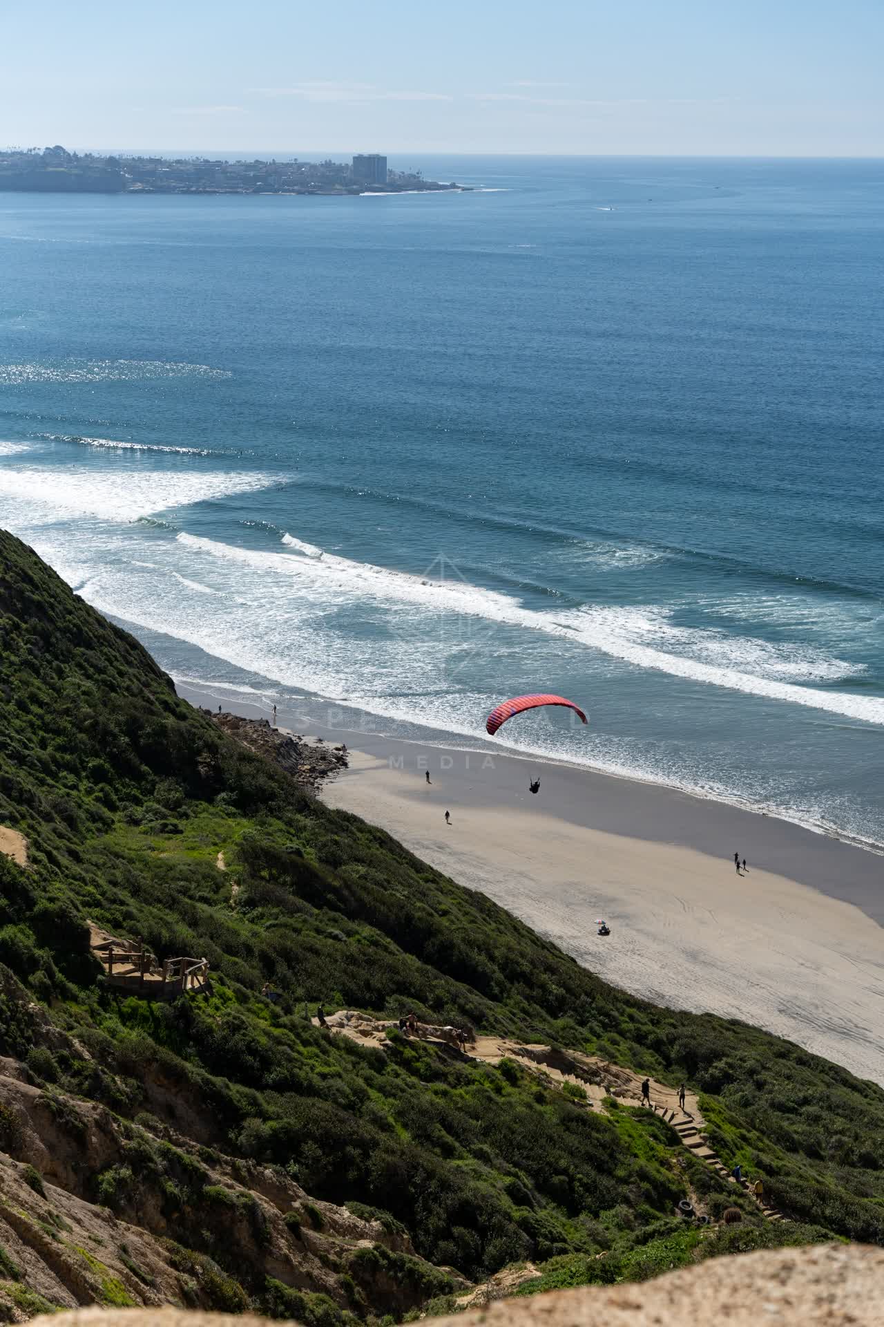 Elevated view of the cliffs, the surf and the ocean at Torrey Pines, with people walking.