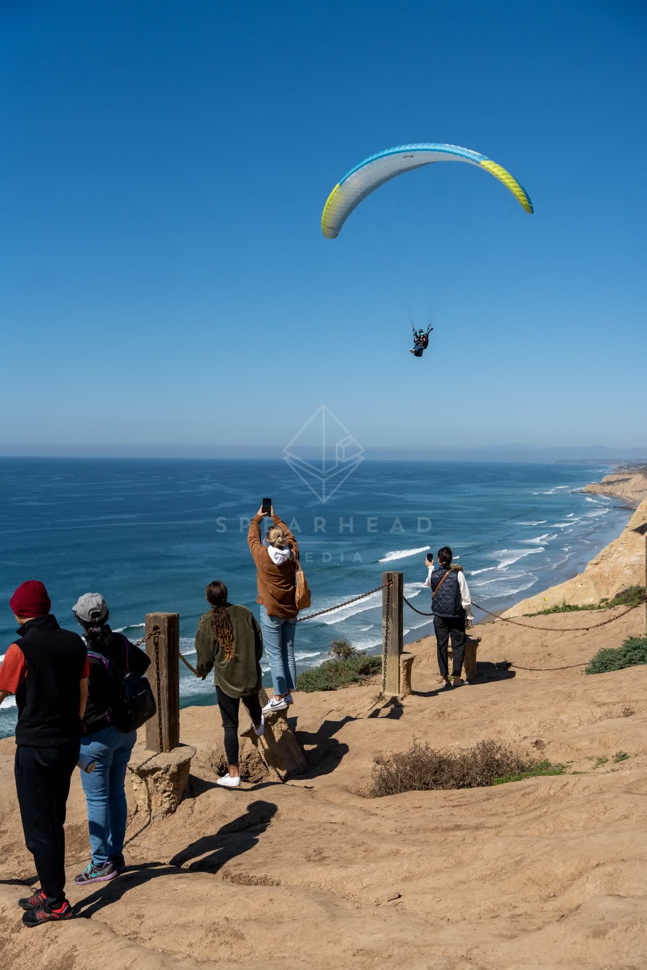 Elevated view of the cliffs, the surf and the ocean at Torrey Pines, with a crowd gathered.