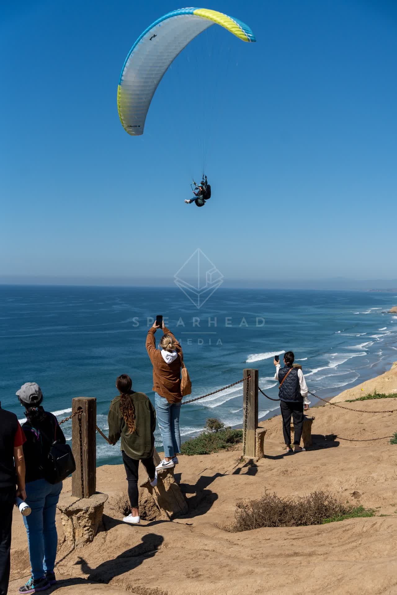 Elevated view of the cliffs, the ocean and open country at Torrey Pines, with a crowd gathered.