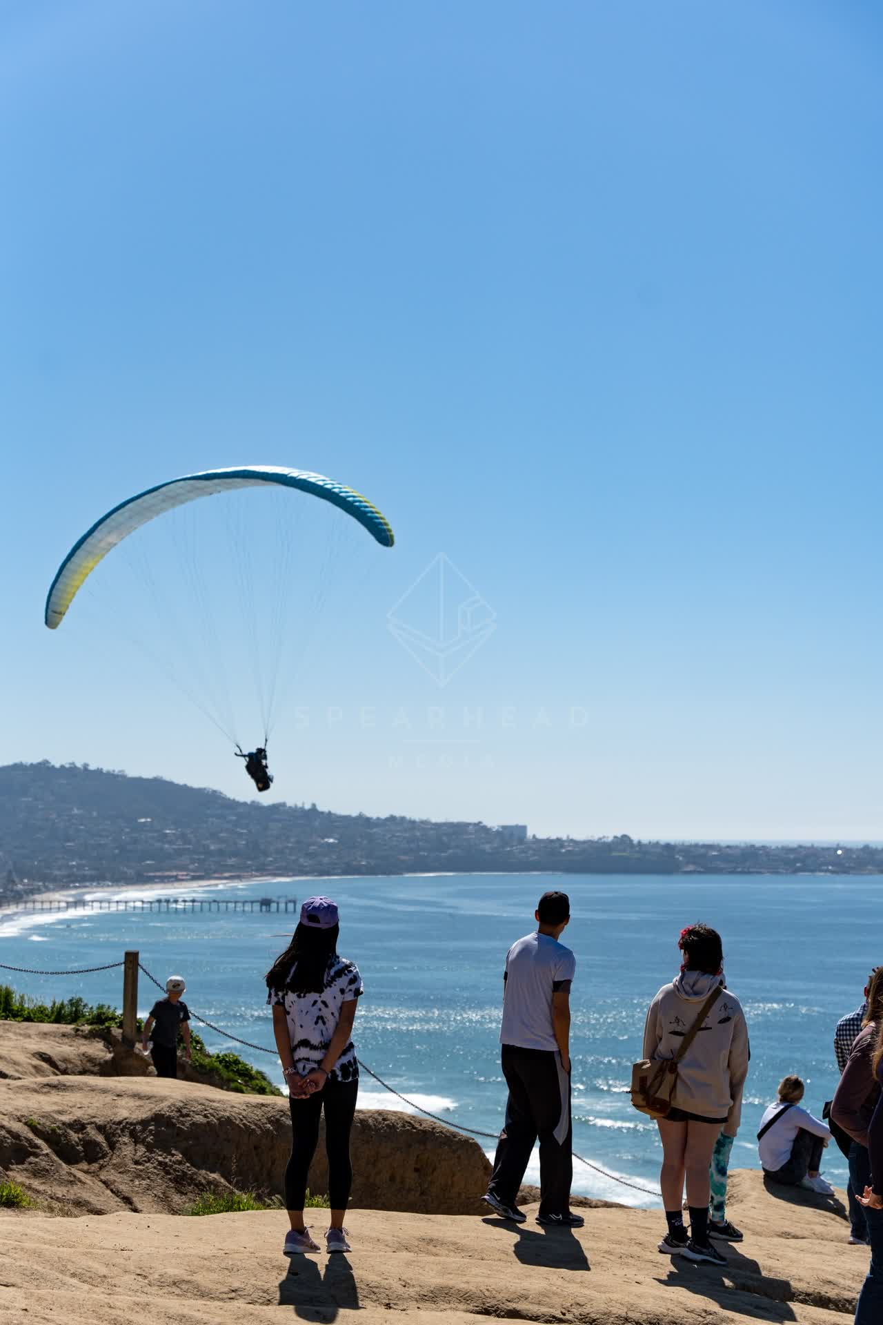 Elevated view of the cliffs, the pier and the ocean at Torrey Pines, with a crowd gathered.