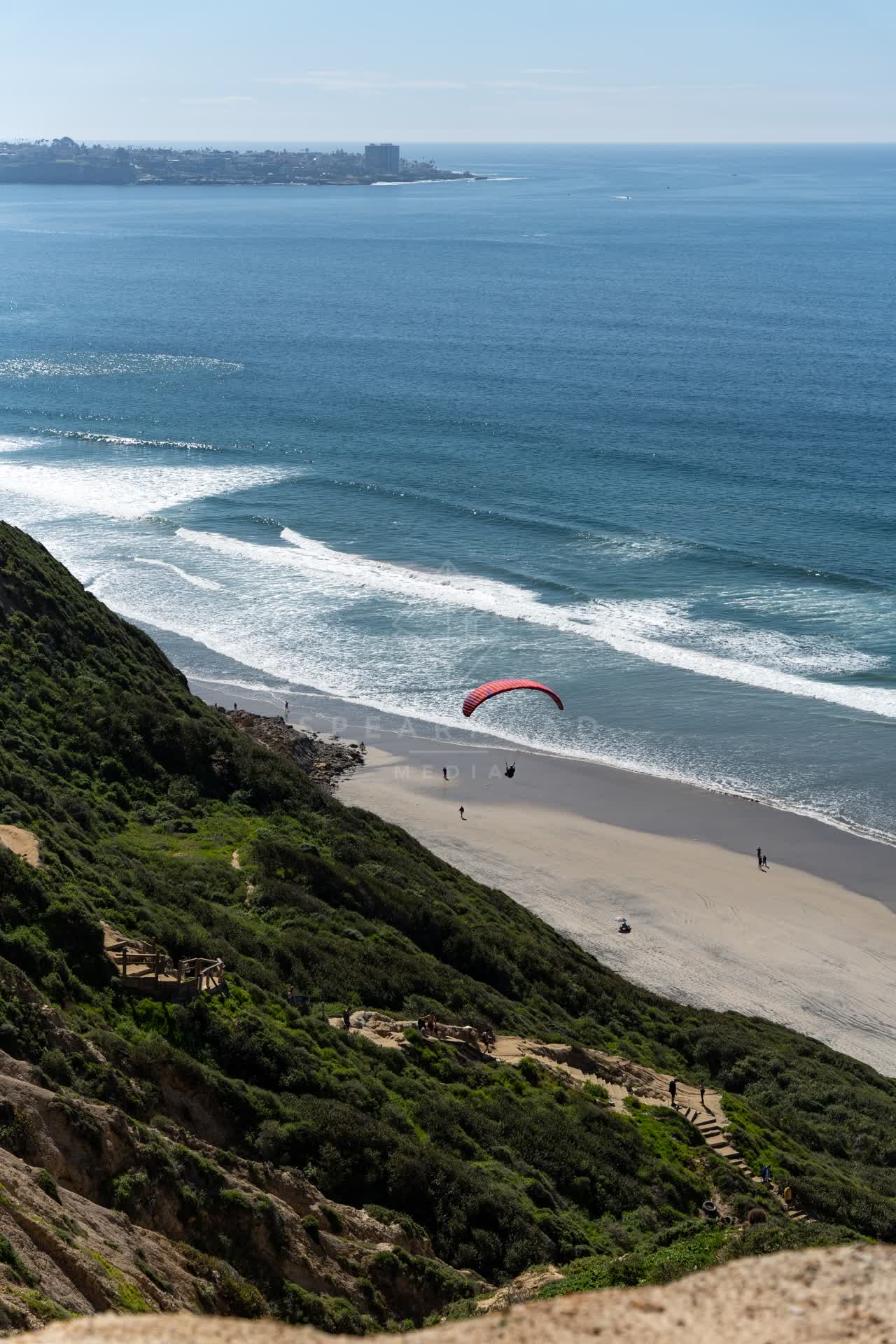 Elevated view of the cliffs, the surf and the ocean at Torrey Pines, with people walking.