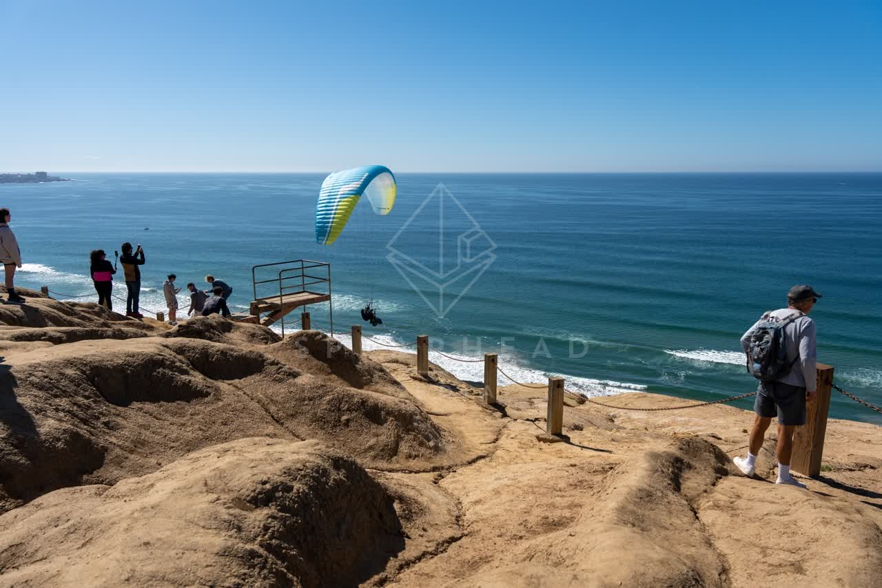 Elevated view of the cliffs, the ocean and open country at Torrey Pines, with a crowd gathered.