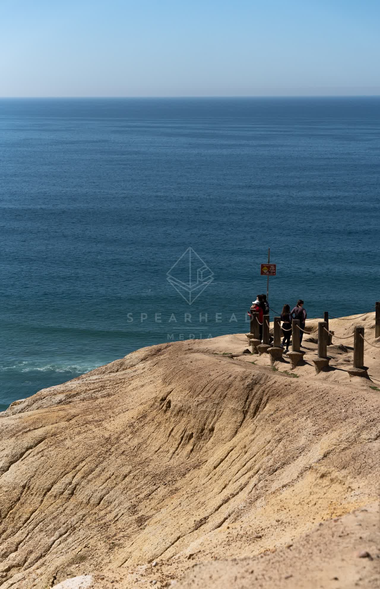 Elevated view of the cliffs, the ocean and open country at Torrey Pines, with people walking.