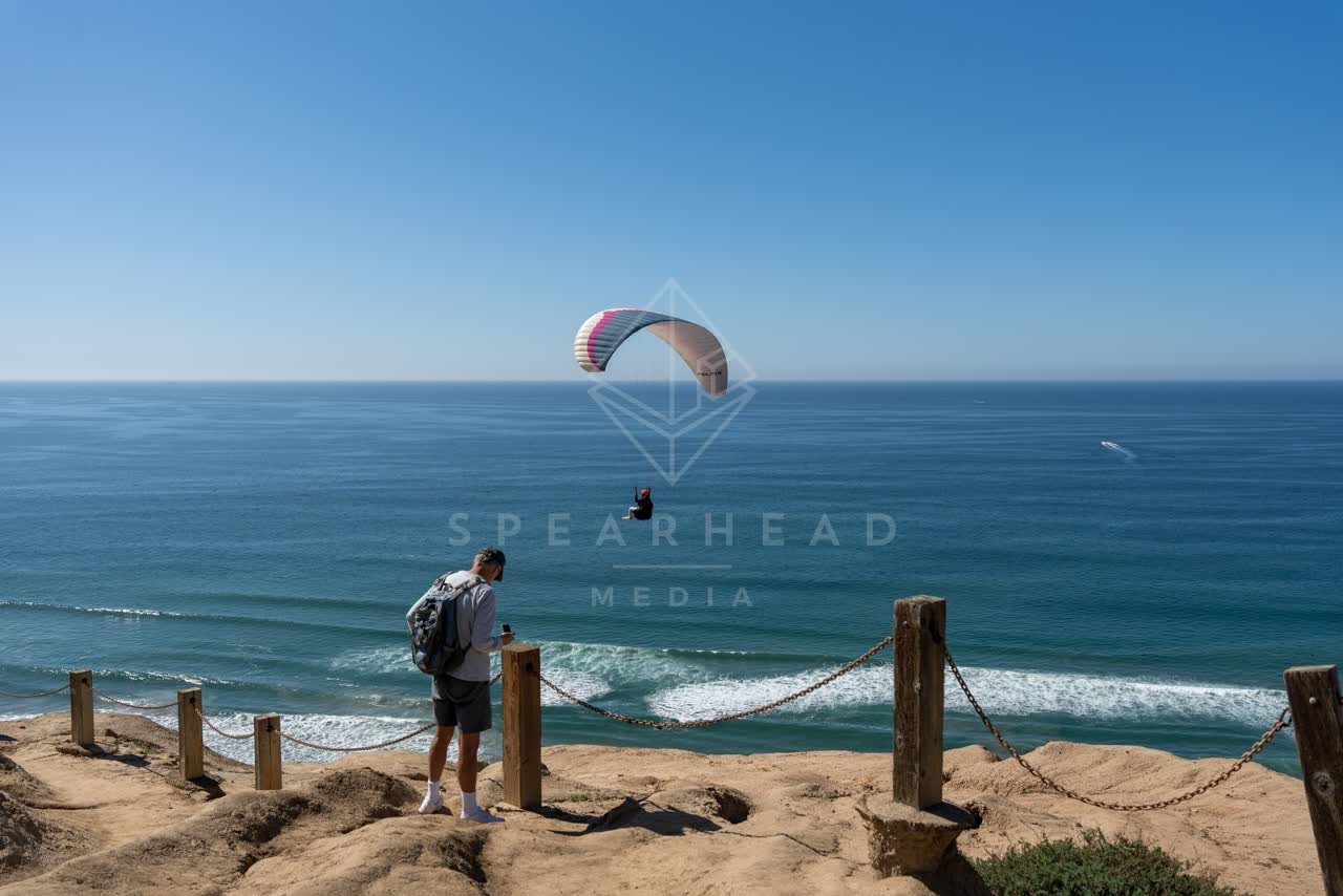 Elevated view of the cliffs, the ocean and open country at Torrey Pines, with a crowd gathered.