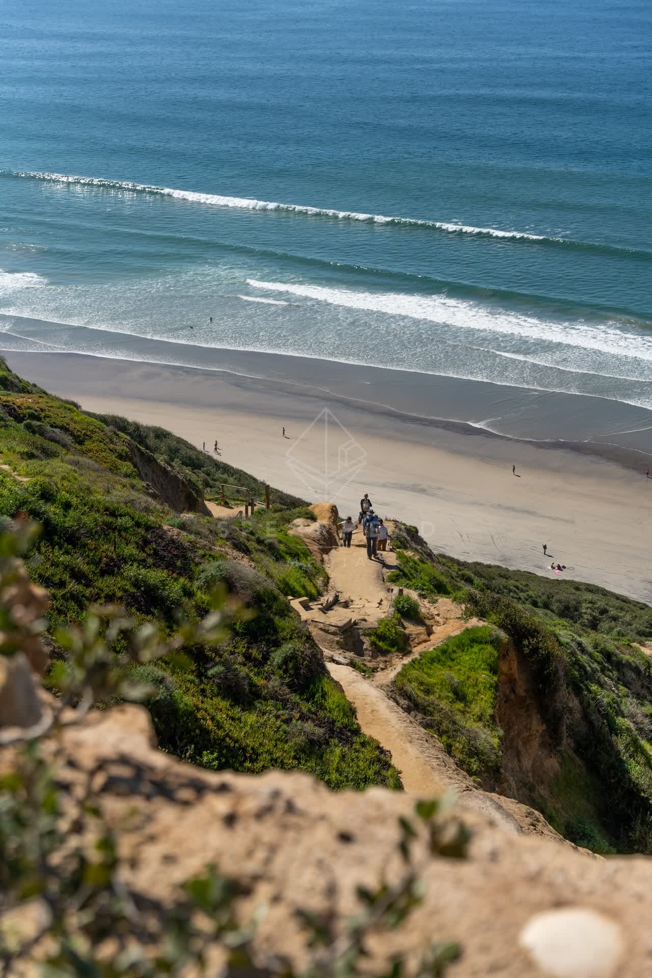 Elevated view of the cliffs, the surf and the ocean at Torrey Pines, with people walking.