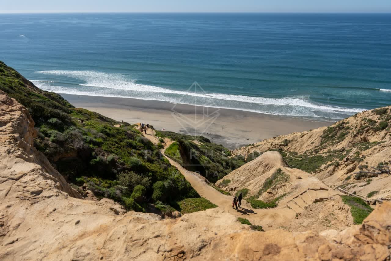 Elevated view of the cliffs, the ocean and the beach at Torrey Pines, with people walking.