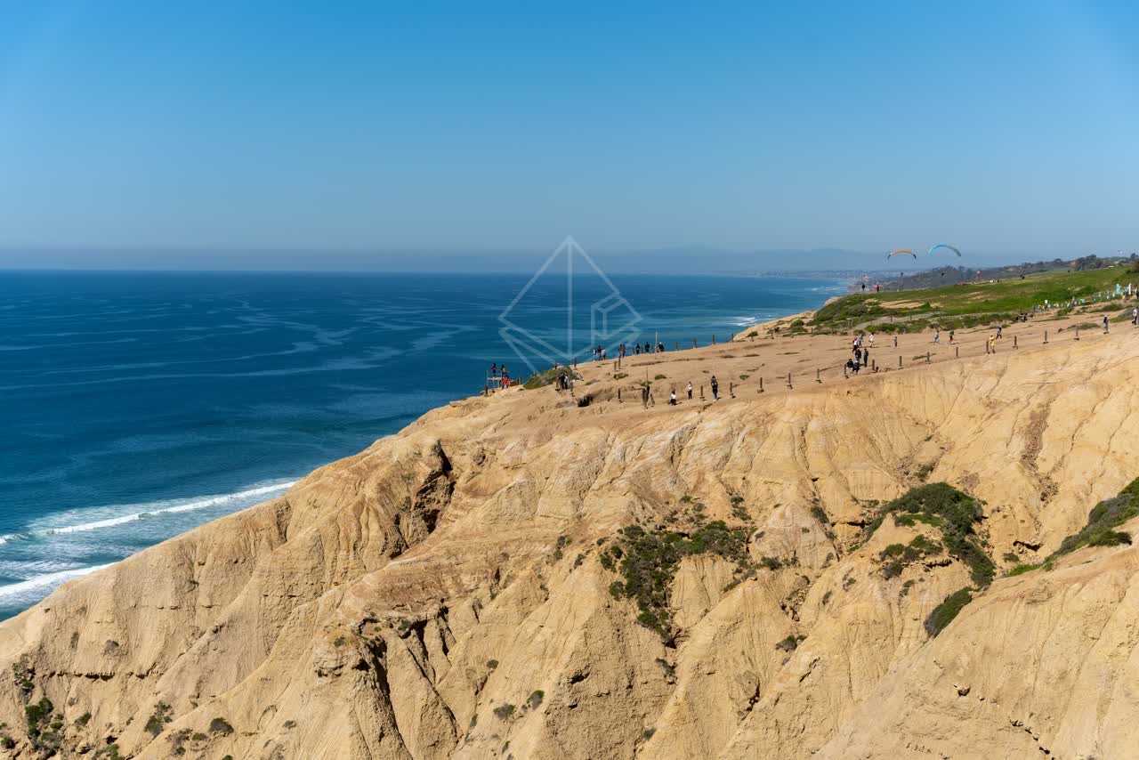 Elevated view of the cliffs, the surf and the ocean at Torrey Pines, with people walking.
