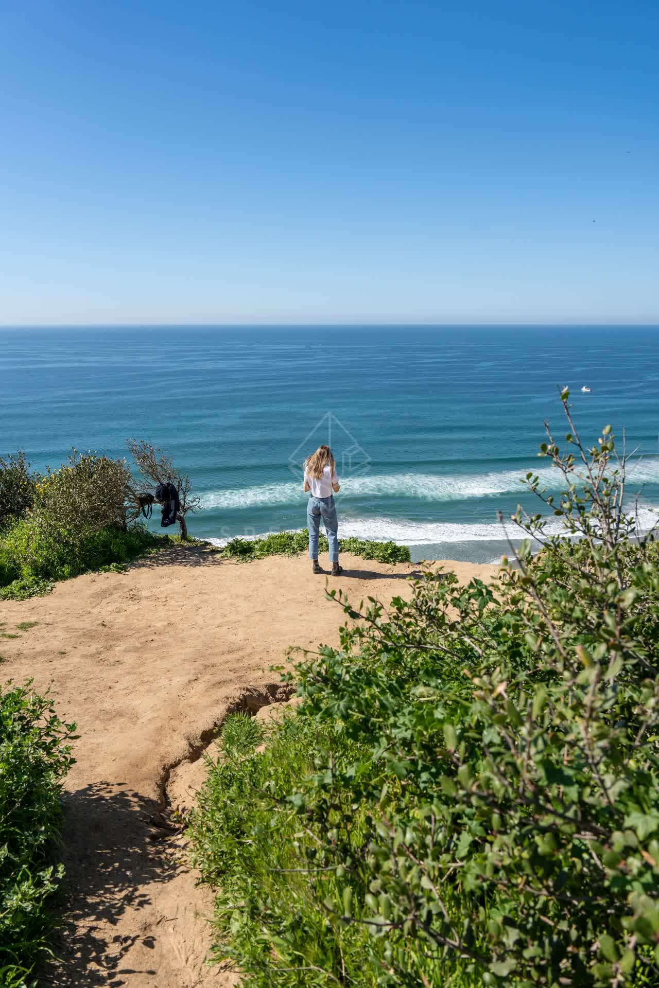 Elevated view of the cliffs, the surf and the ocean at Torrey Pines, with people walking.