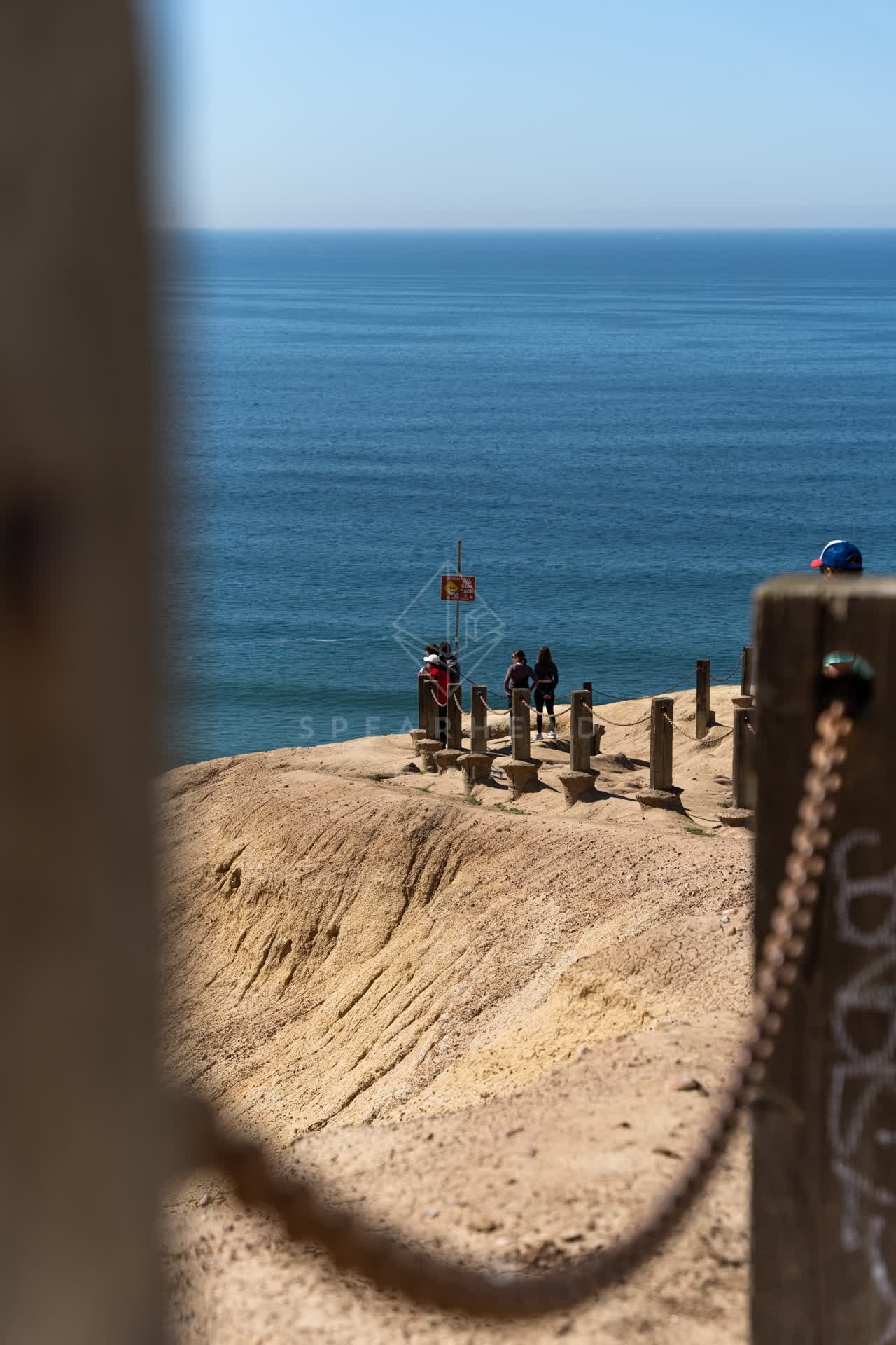 Elevated view of the cliffs, the ocean and open country at Torrey Pines, with people walking.