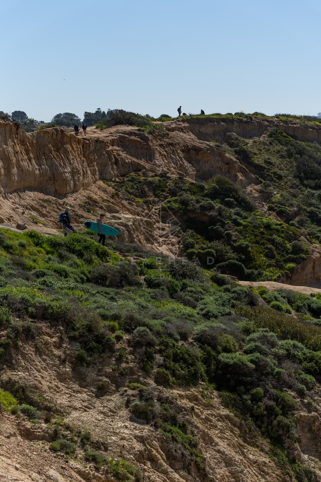 Elevated view of the cliffs and open country at Torrey Pines, with people walking.