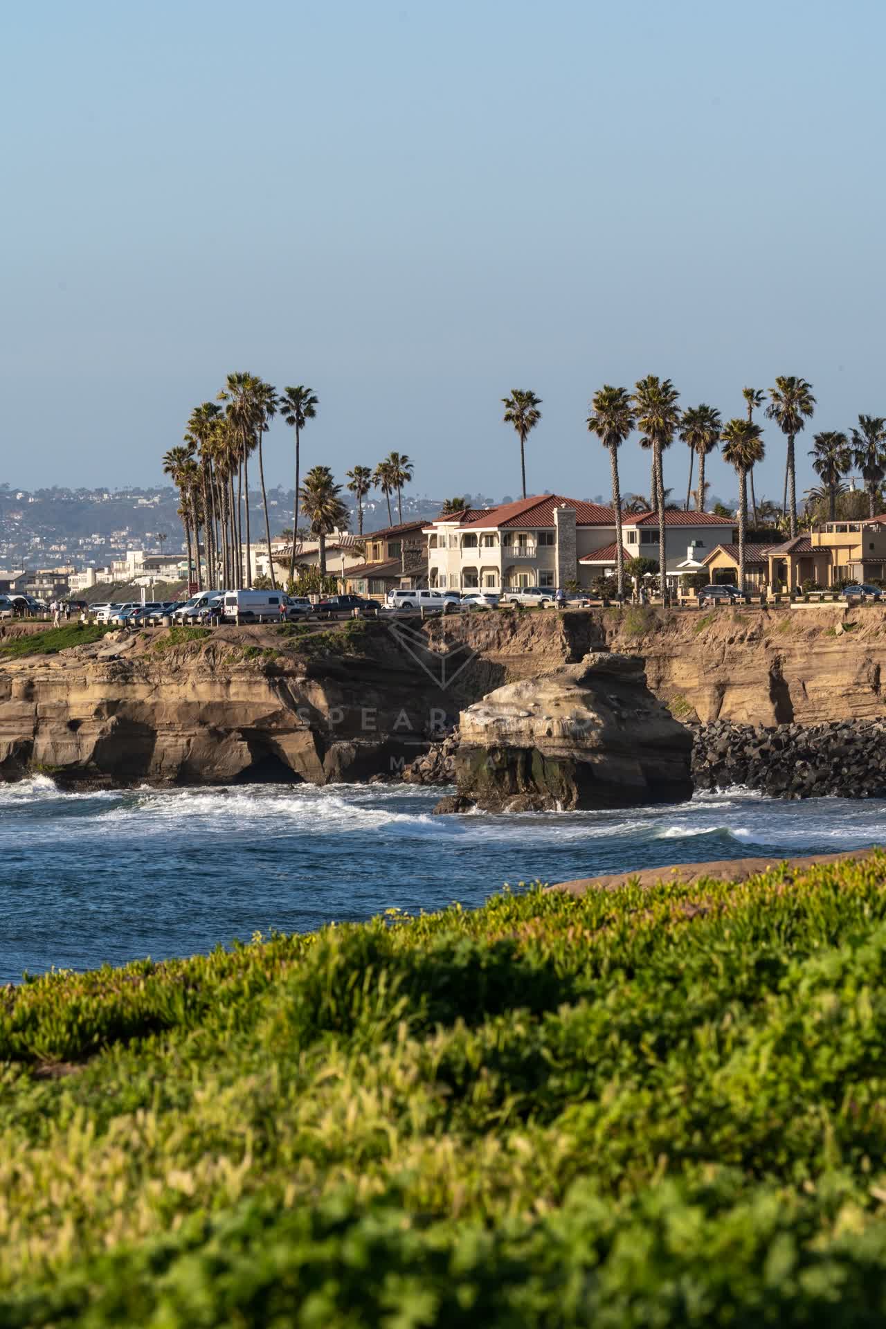 Elevated view of the cliffs, the surf and palm trees at Sunset Cliffs.