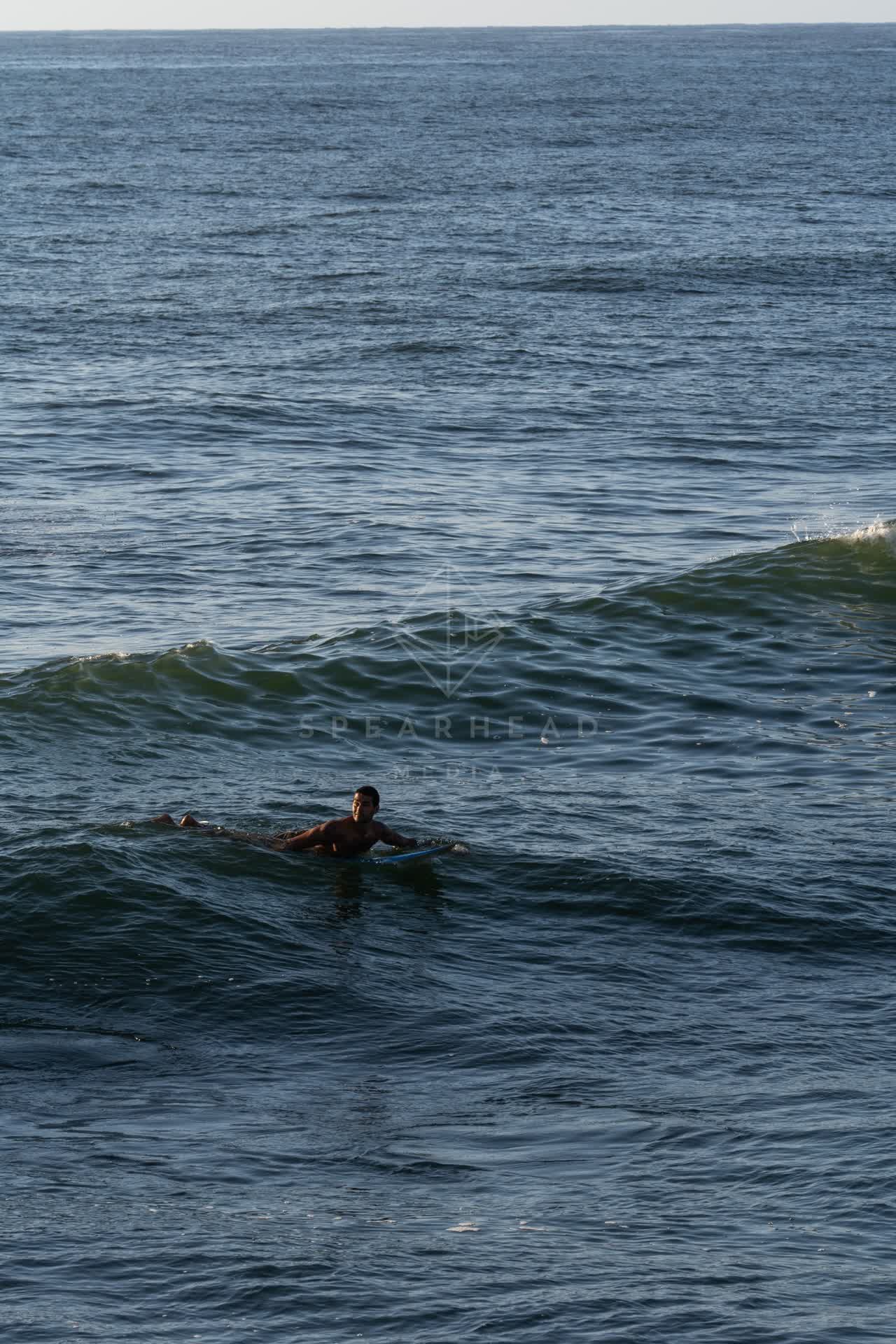 The beach, the surf and the ocean at Sunset Cliffs, with paddlers on the water.