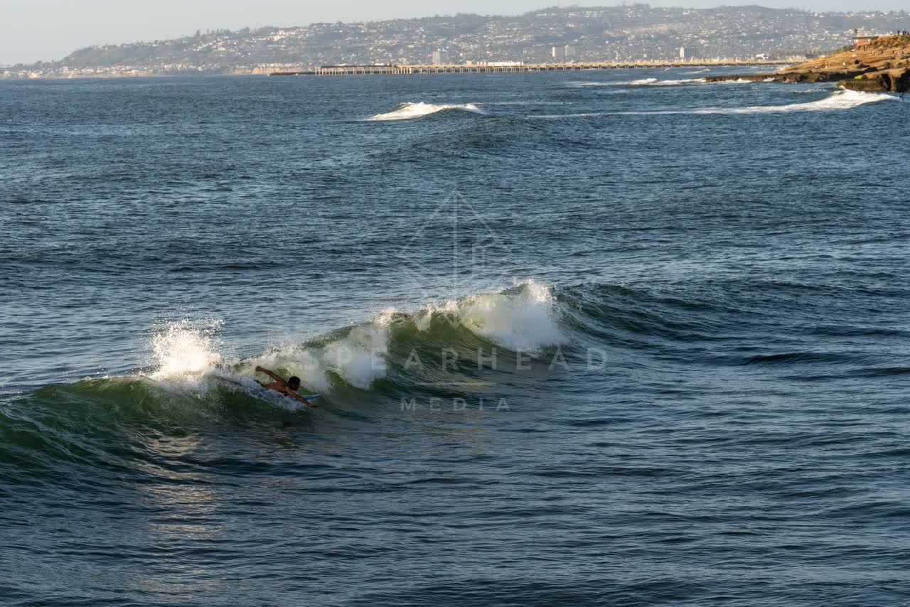 The cliffs, the surf and the pier at Sunset Cliffs, with surfers out.