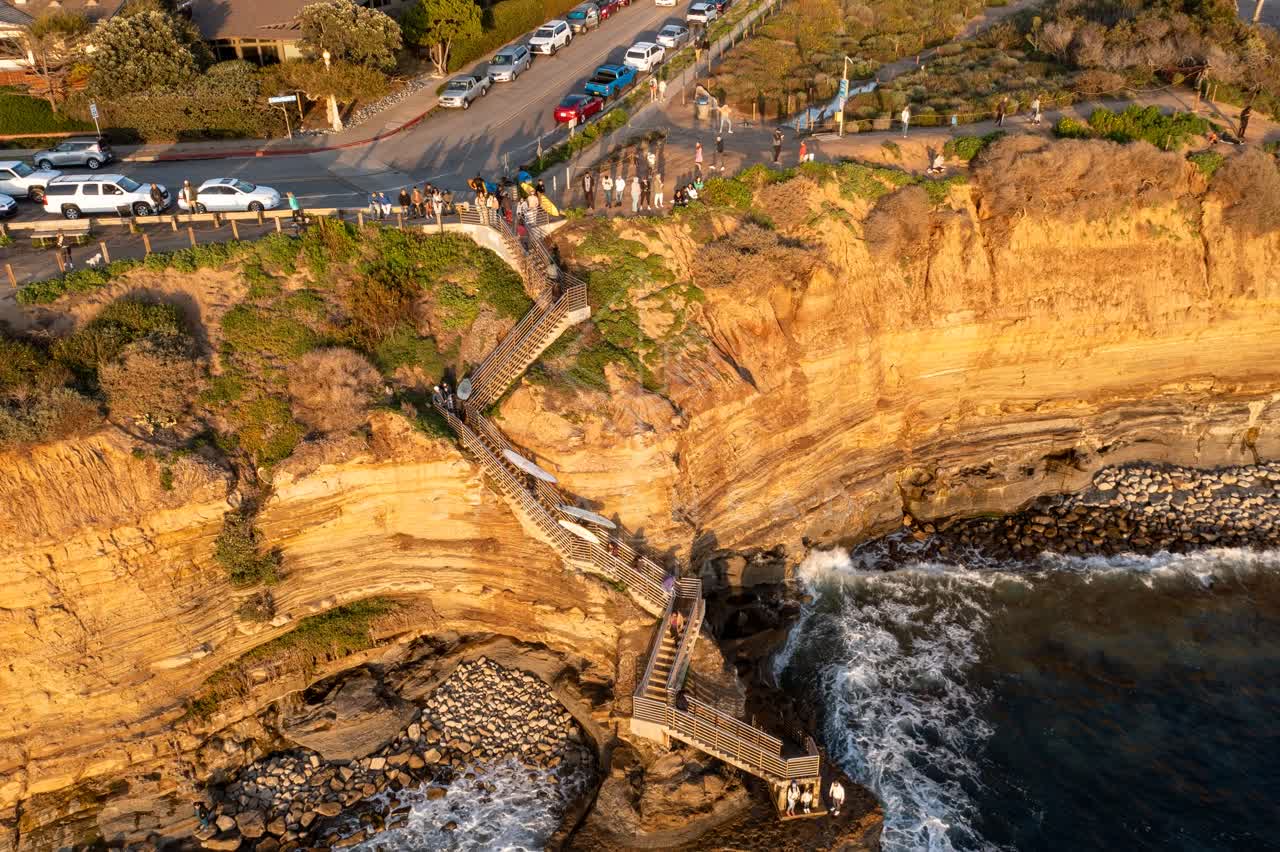 Aerial view of the cliffs, the surf and the ocean at Sunset Cliffs, with people walking.