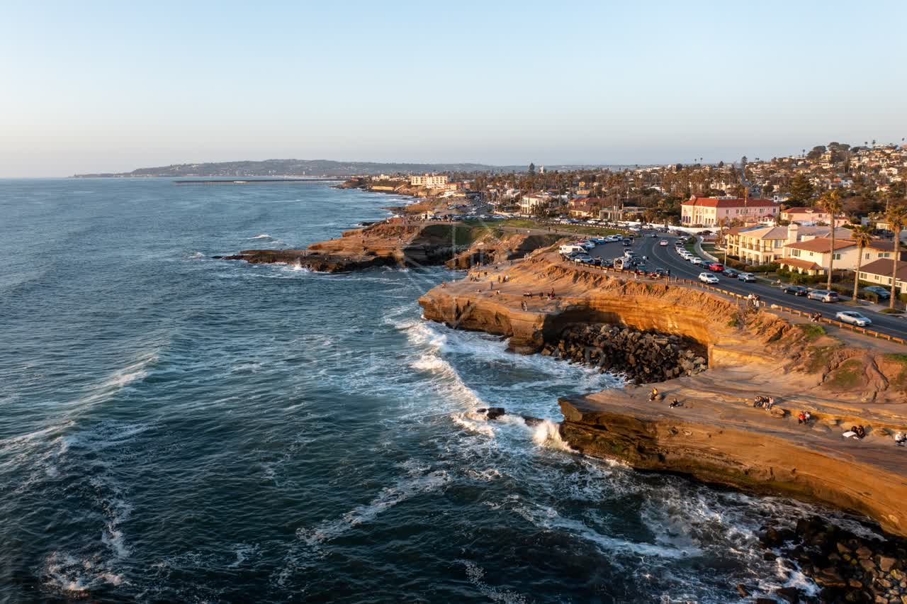 Aerial view of the cliffs, the surf and palm trees at Sunset Cliffs, with people walking.