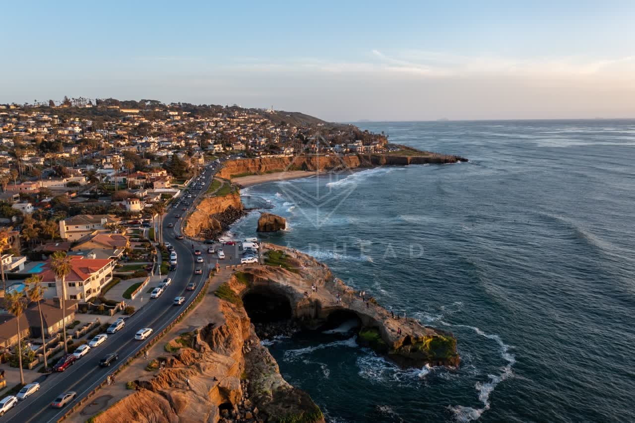 Aerial view of the cliffs, palm trees and the ocean at Sunset Cliffs, with people walking.