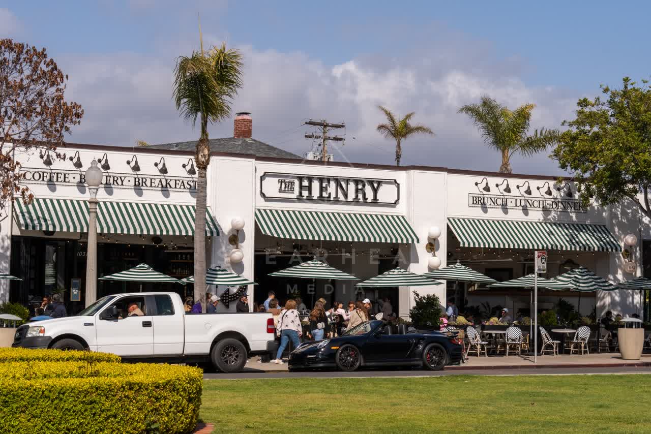 The downtown streets, palm trees and the buildings in Coronado, with people eating outside.