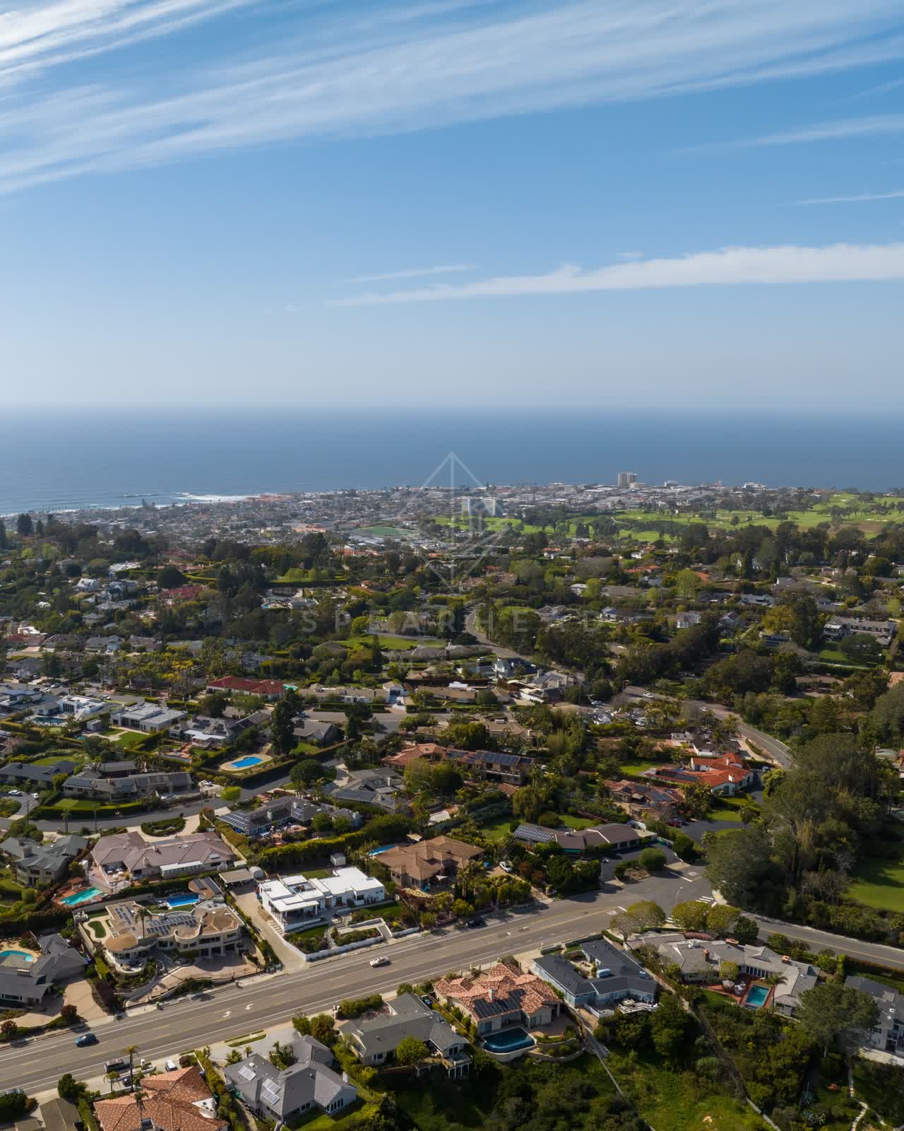 Aerial view of a residential street, palm trees and the ocean at La Jolla Mesa.