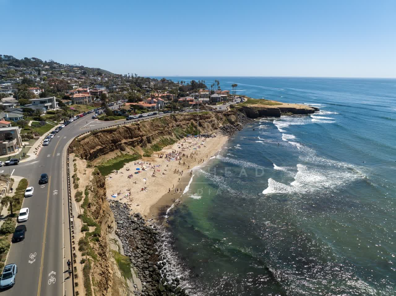 Aerial view of the cliffs, the surf and the ocean at Sunset Cliffs, with people walking.