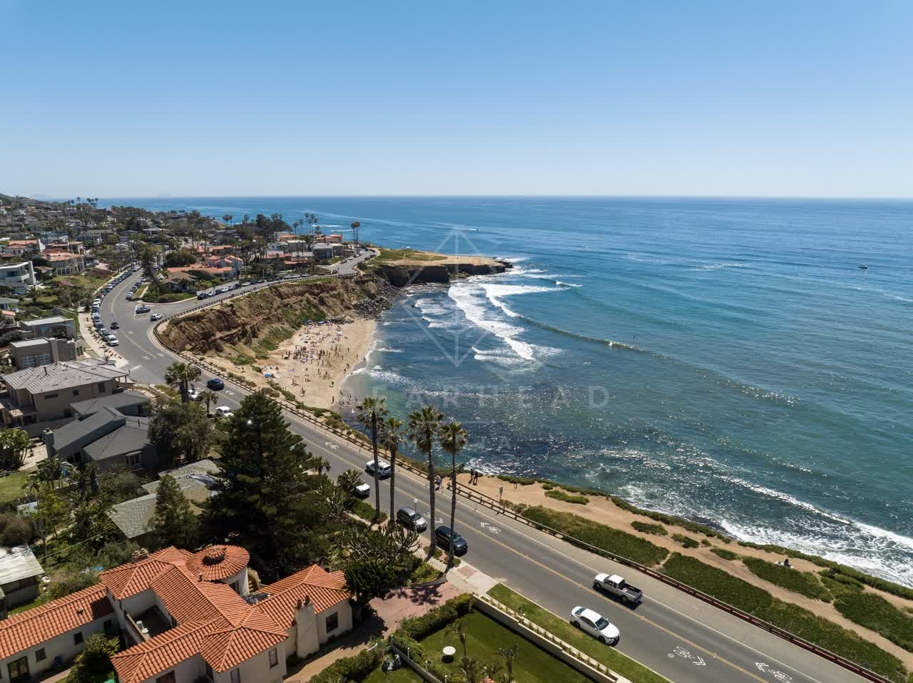 Aerial view of the cliffs, the surf and palm trees at Sunset Cliffs, with people walking.