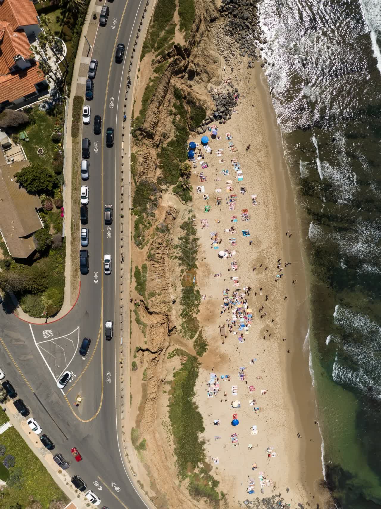 Aerial view of the beach, the surf and the ocean at Sunset Cliffs, with a crowd gathered.