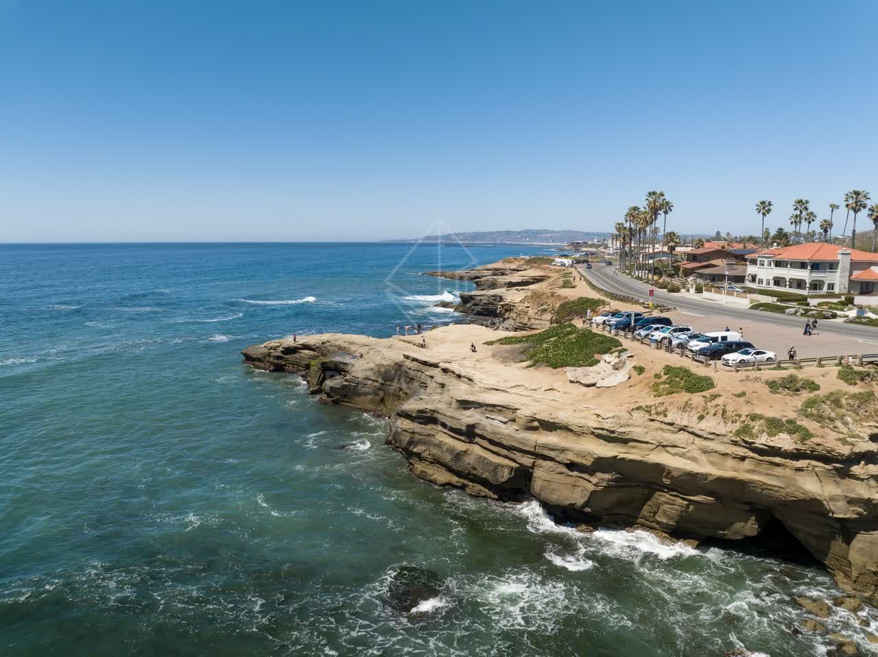 Aerial view of the cliffs, the surf and palm trees at Sunset Cliffs, with people walking.