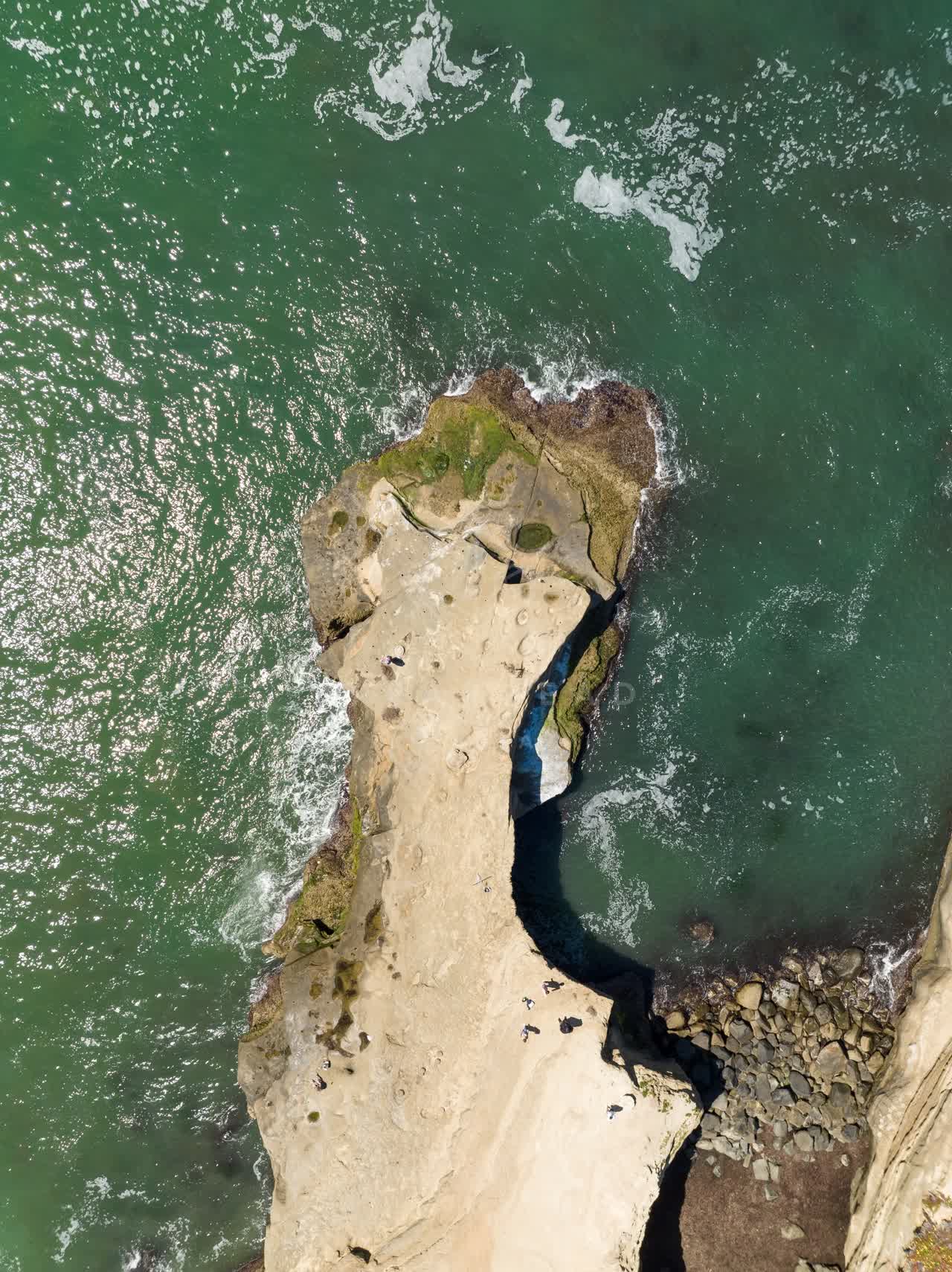 Aerial view of the cliffs, the surf and the ocean at Sunset Cliffs, with people walking.