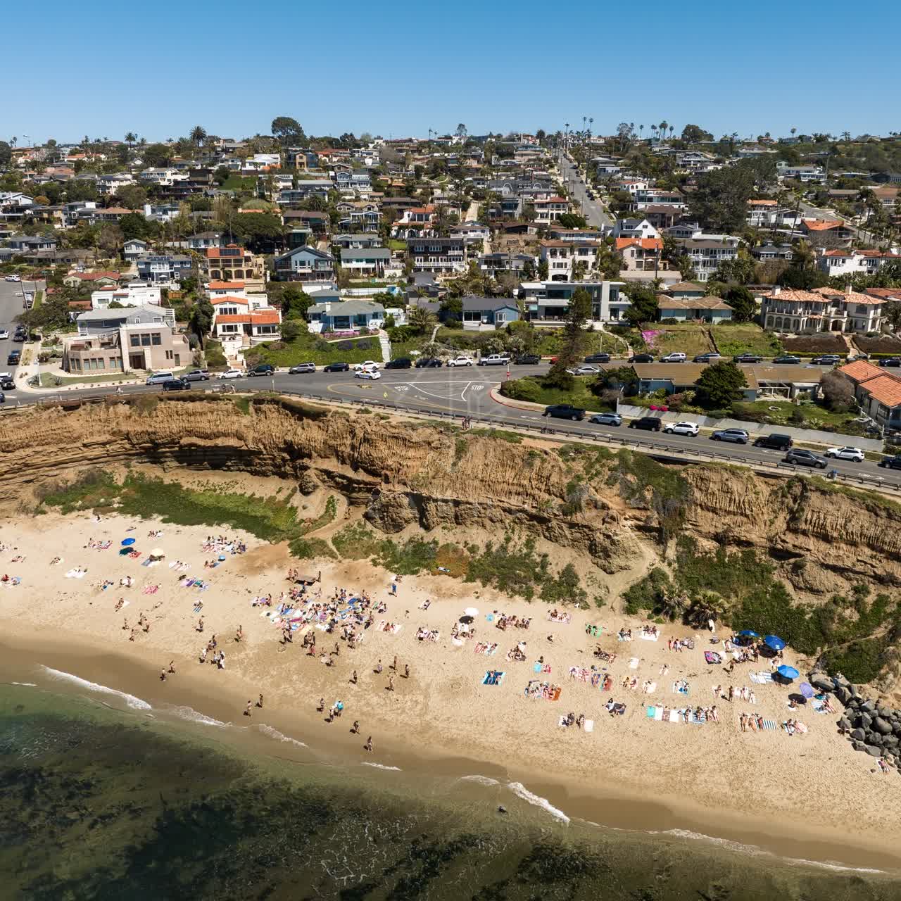 Aerial view of the cliffs, the ocean and homes at Sunset Cliffs, with a crowd gathered.