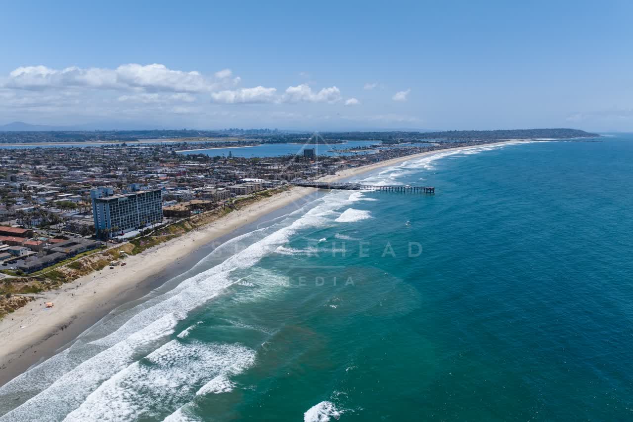 Aerial view of the beach, the surf and the pier at Tourmaline, with surfers out.