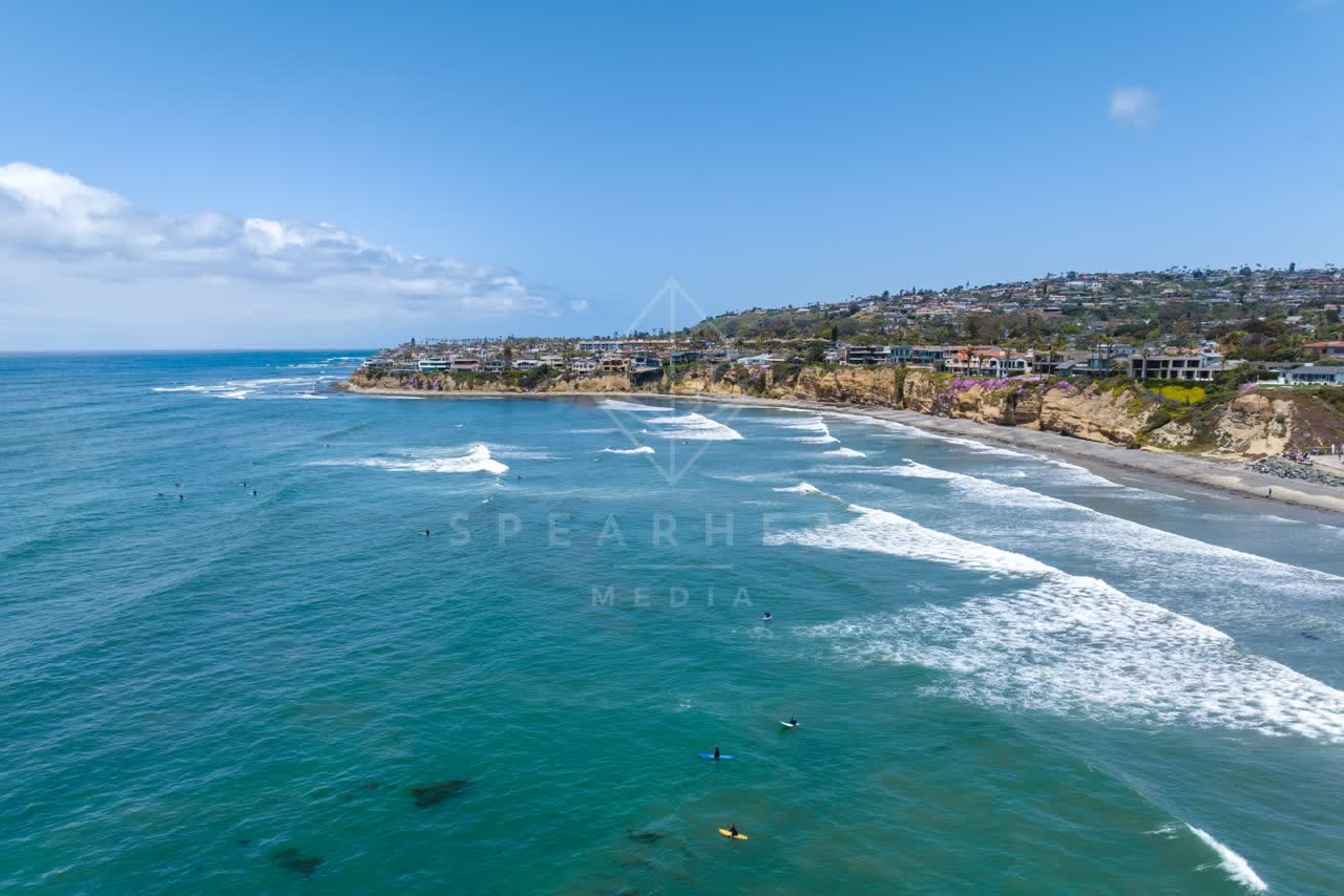 Aerial view of the cliffs, the surf and the ocean at Tourmaline, with surfers out.