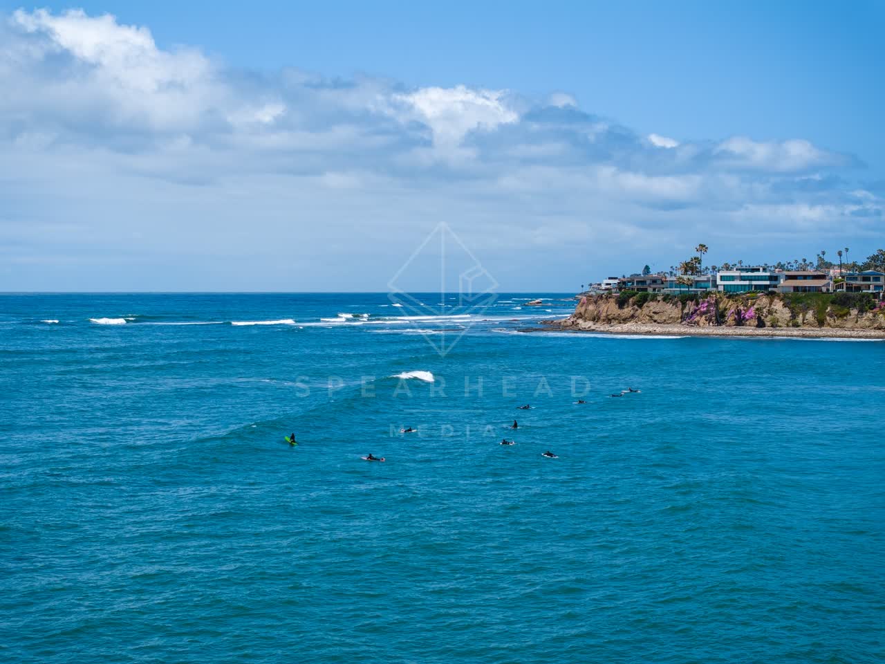 Low aerial view of the beach, the surf and the ocean at Tourmaline, with surfers out.