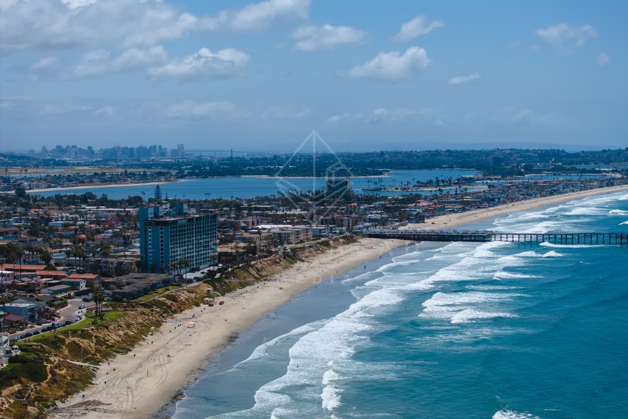 Aerial view of the beach, the surf and the pier at Tourmaline, with people walking.