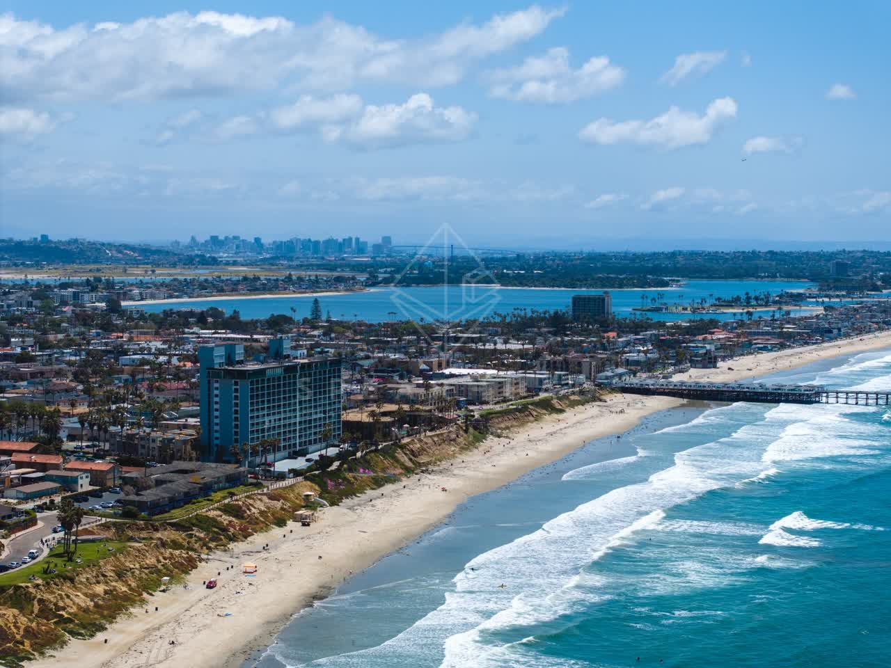 Aerial view of the beach, the surf and the pier at Tourmaline, with people walking.