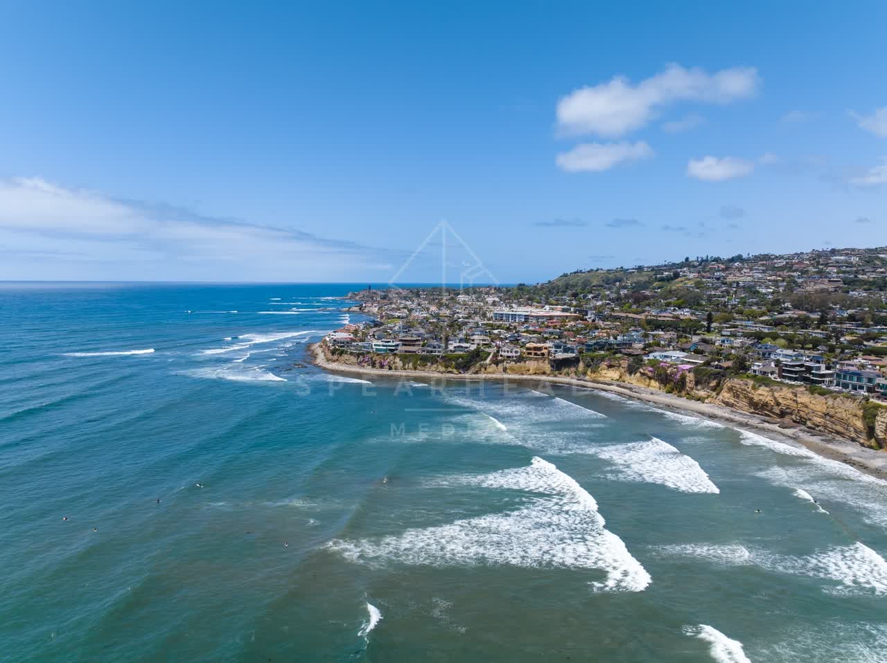 Aerial view of the cliffs, the surf and the ocean at Tourmaline, with surfers out.