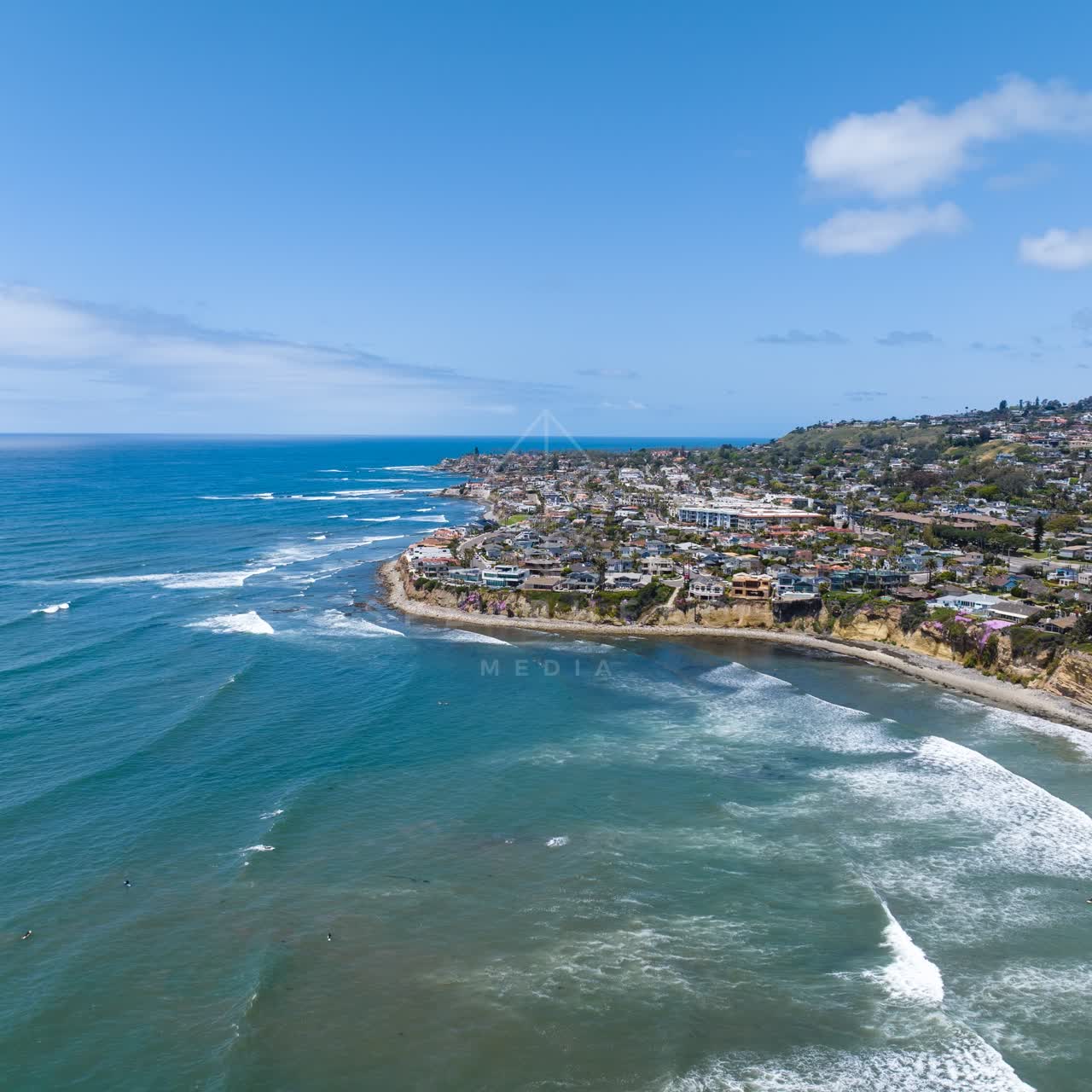 Aerial view of the cliffs, the surf and the ocean at Tourmaline, with surfers out.