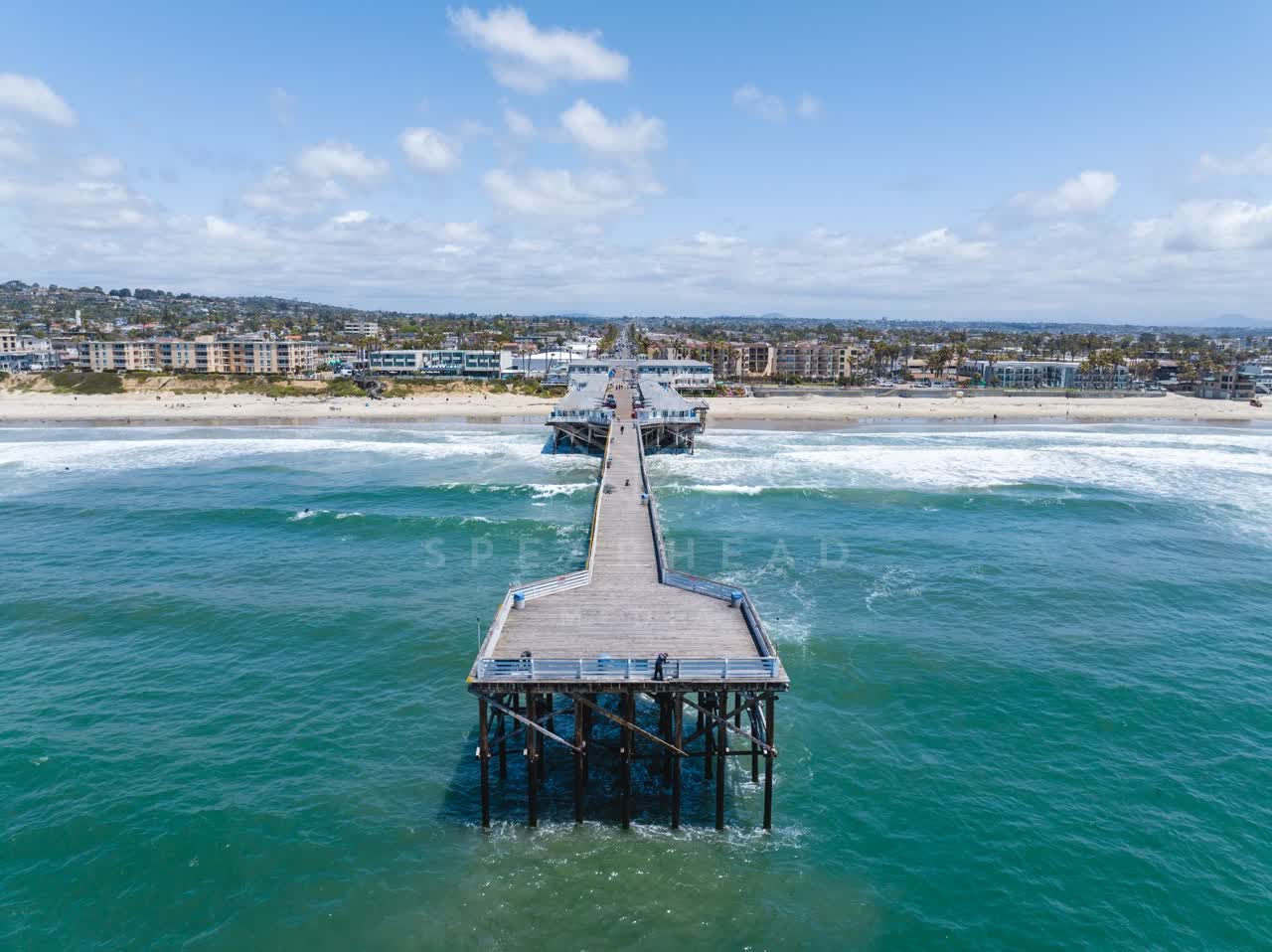 Aerial view of the beach, the surf and the pier in Pacific Beach, with people walking.
