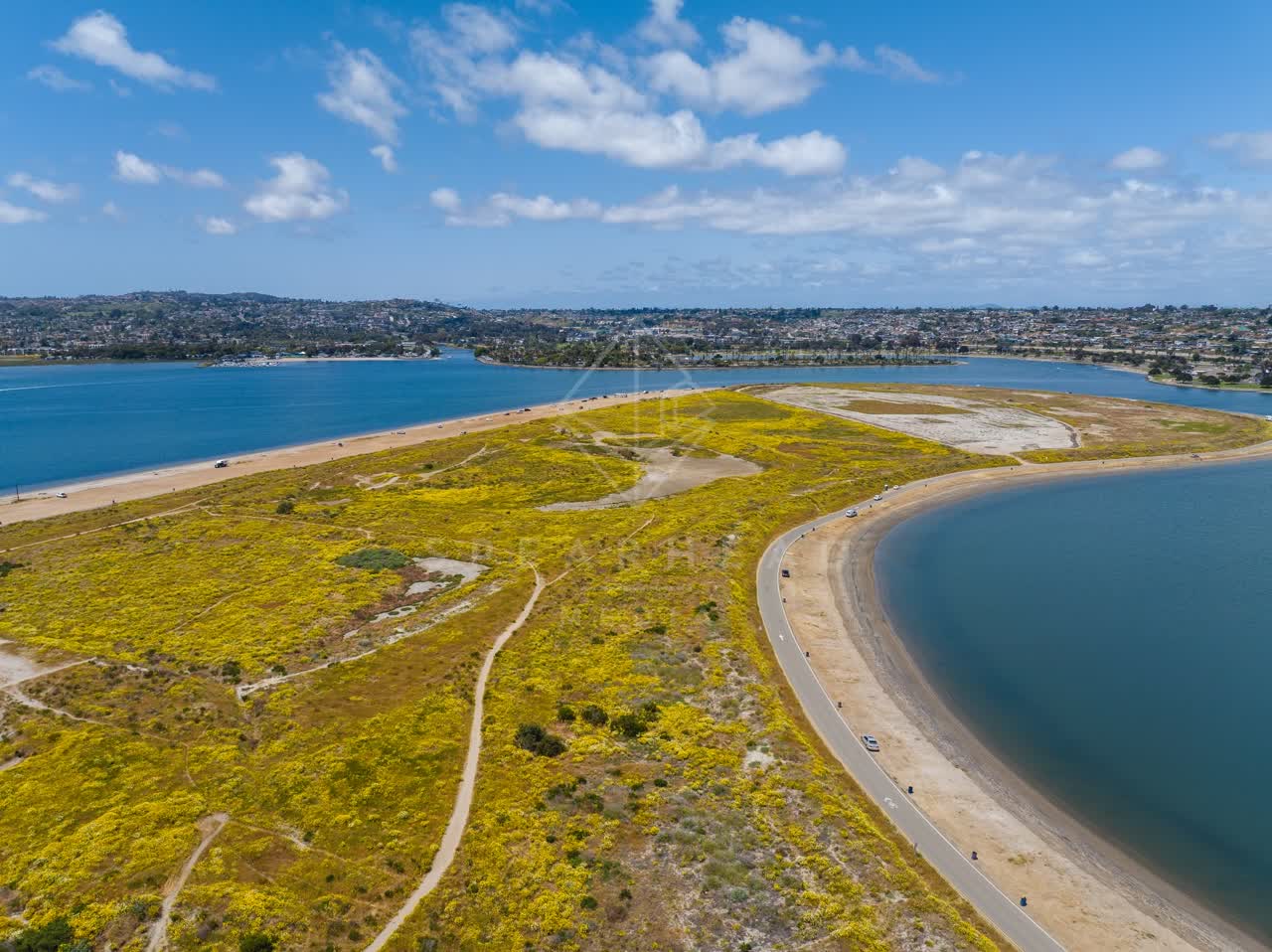 Aerial view of a park, the bay and homes in Mission Bay, with people walking.