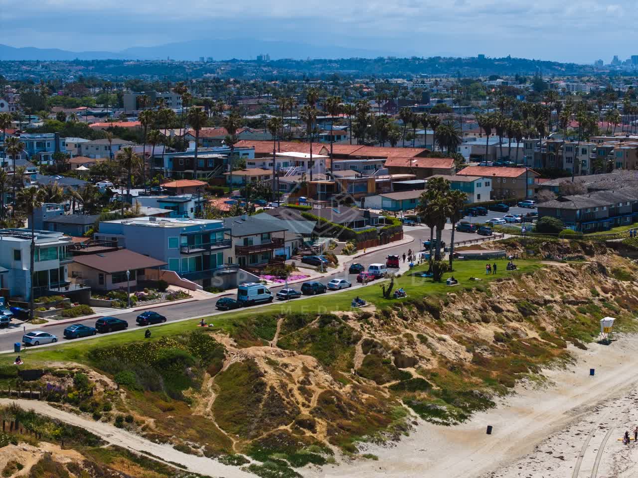 Aerial view of a residential street, palm trees and the ocean at Tourmaline, with people walking.