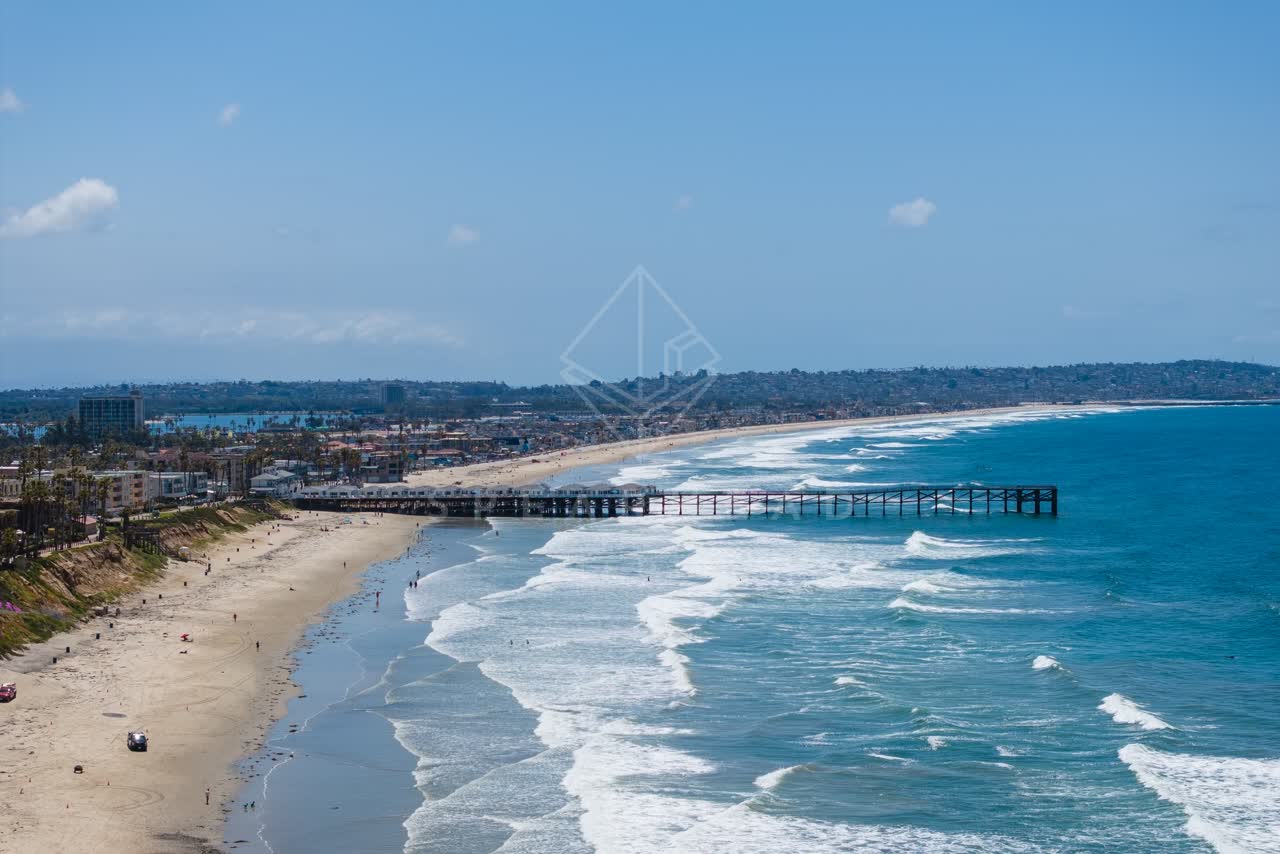 Aerial view of the beach, the surf and the pier in Pacific Beach, with people walking.