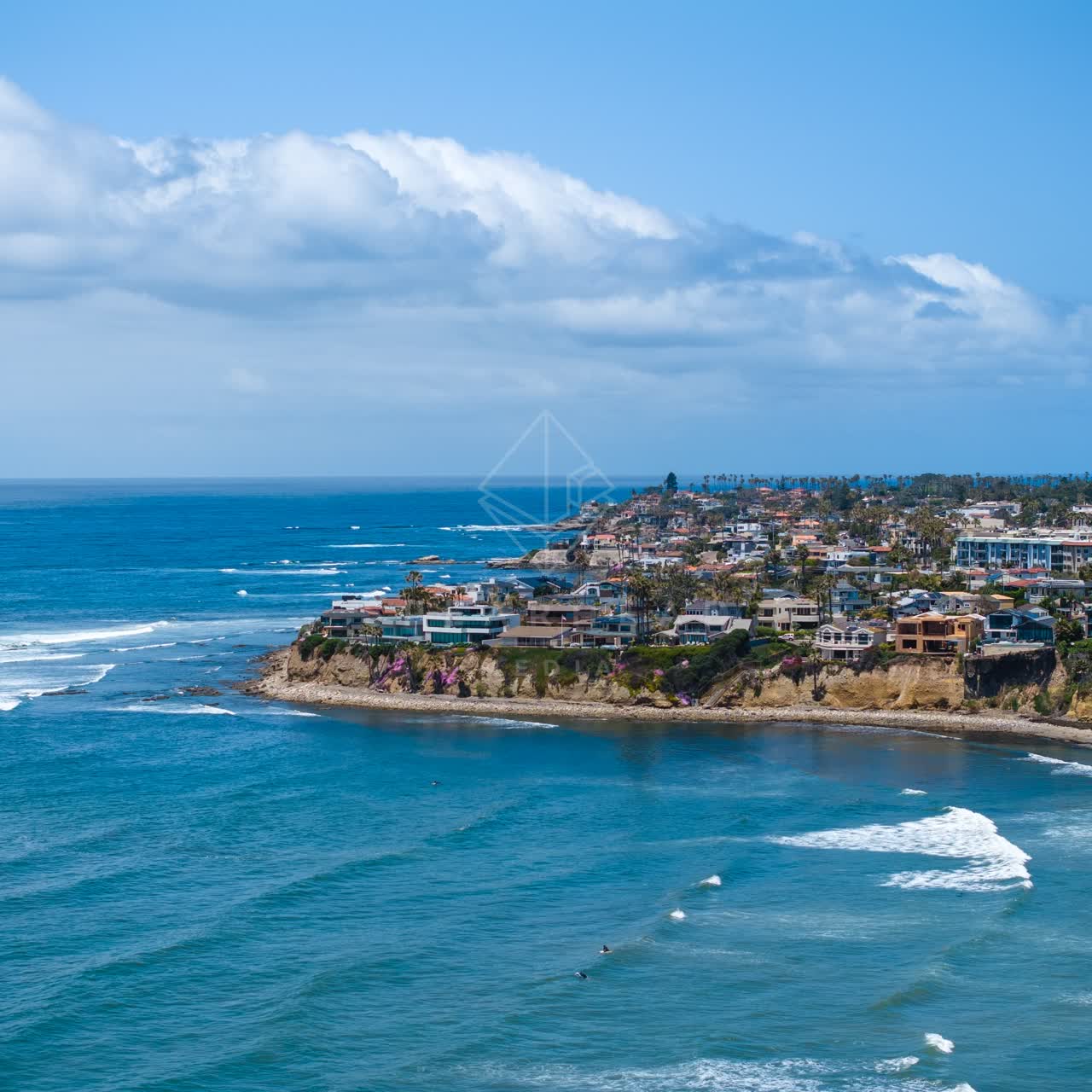 Aerial view of the cliffs, the surf and palm trees at Bird Rock, with surfers out.