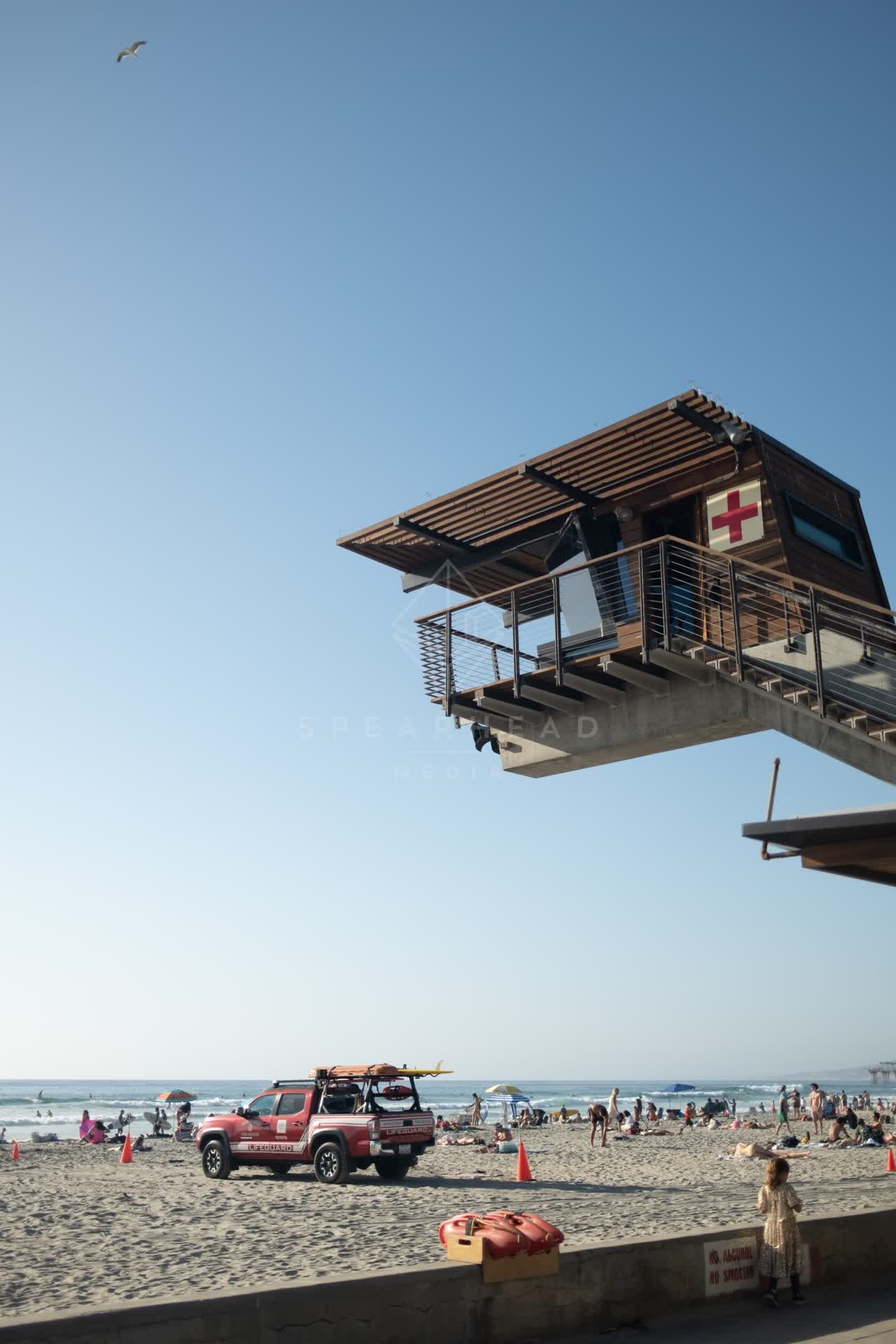 Elevated view of the beach, the surf and the pier at La Jolla Shores, with people walking.