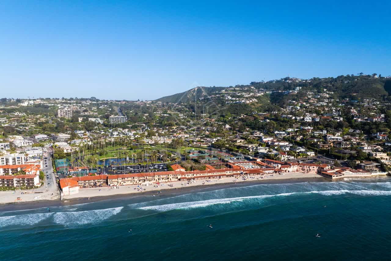 Aerial view of the beach, the surf and palm trees at La Jolla Shores, with swimmers in the water.